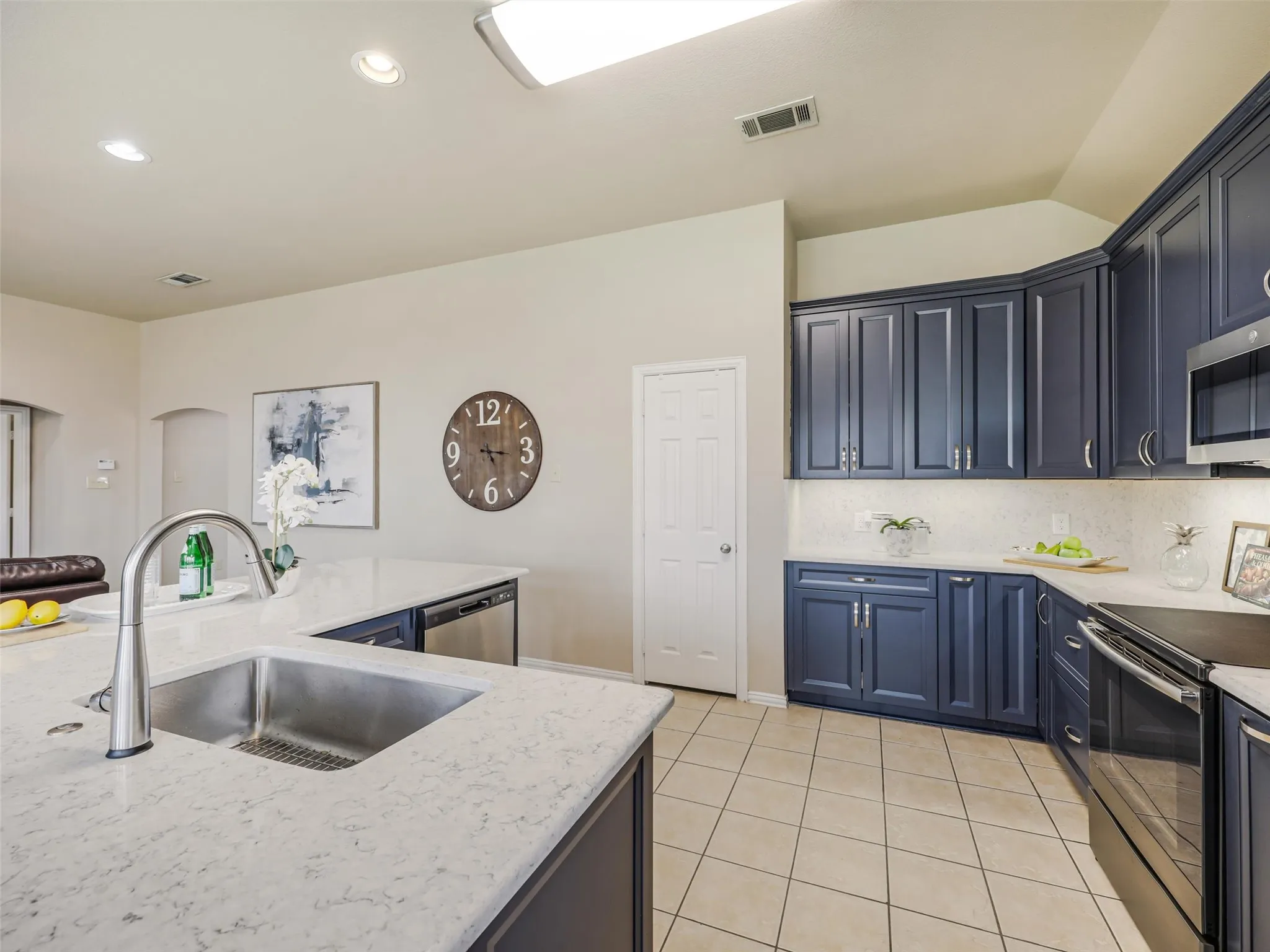 Kitchen features include a stainless steel undermount sink, high-arc faucet, light countertops, blue cabinetry, and a pantry for additional storage.