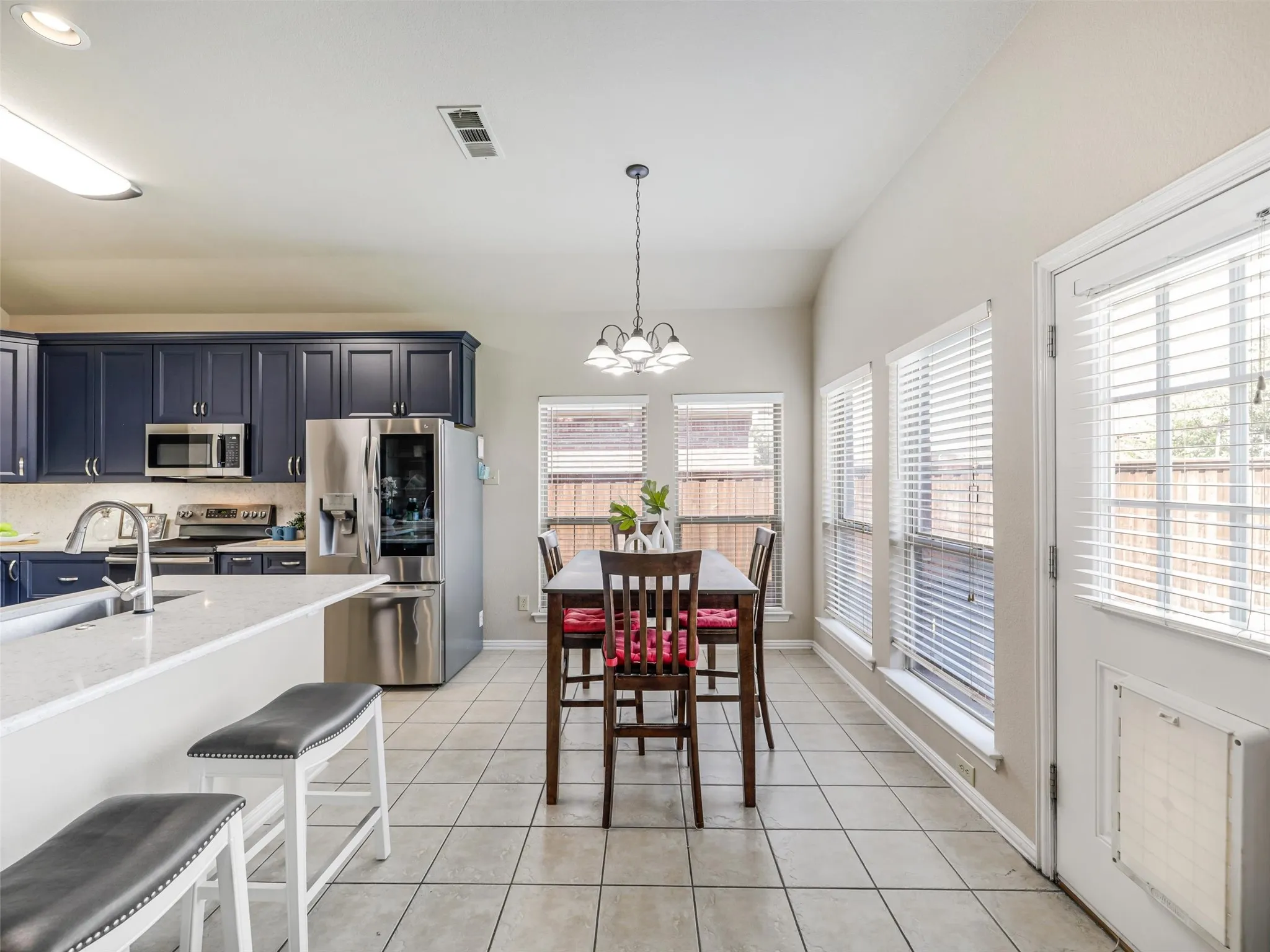 Bright breakfast nook features a decorative chandelier, surrounding windows, and convenient access to the backyard.