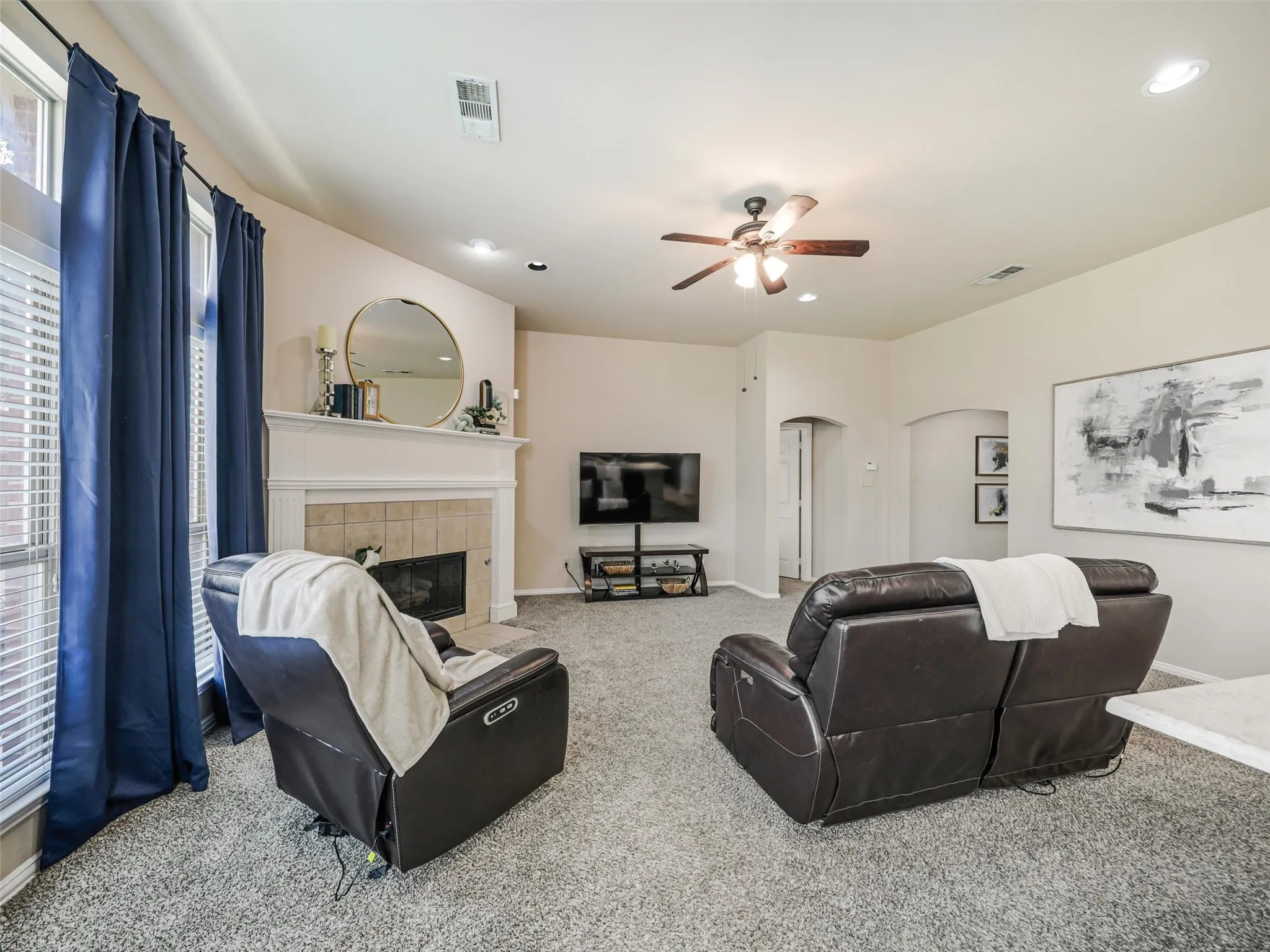 Large windows brighten this inviting living space, featuring a fireplace, generous seating area, and arched doorways leading to adjoining rooms.