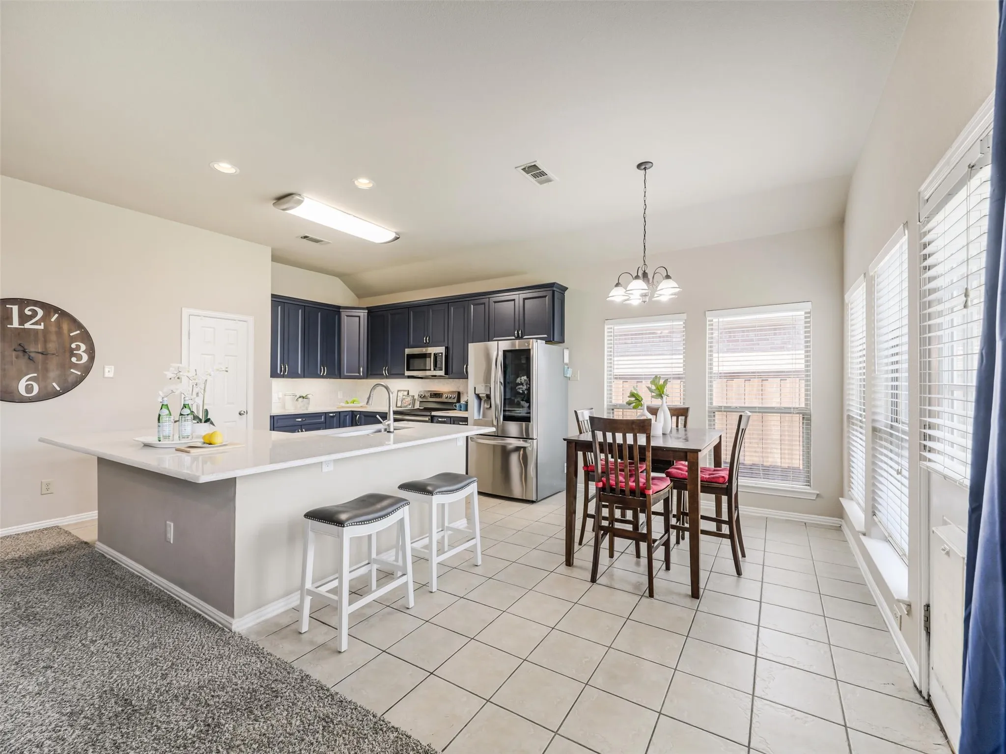 Breakfast bar seating and an adjoining dining nook provide convenient gathering spaces in this open kitchen, with windows bringing in abundant natural light.