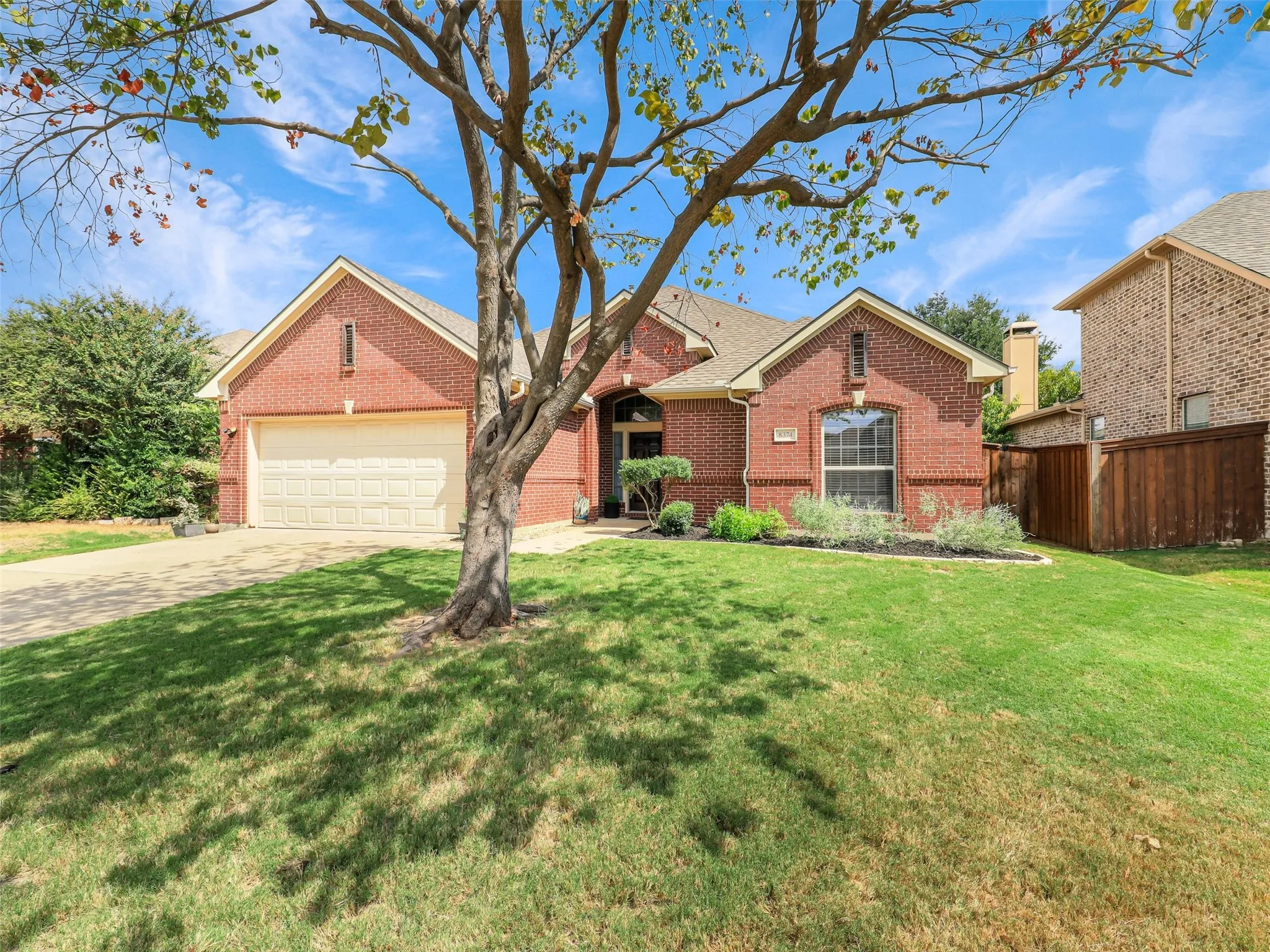 A spacious front lawn and mature tree frame the home’s attractive brick exterior.