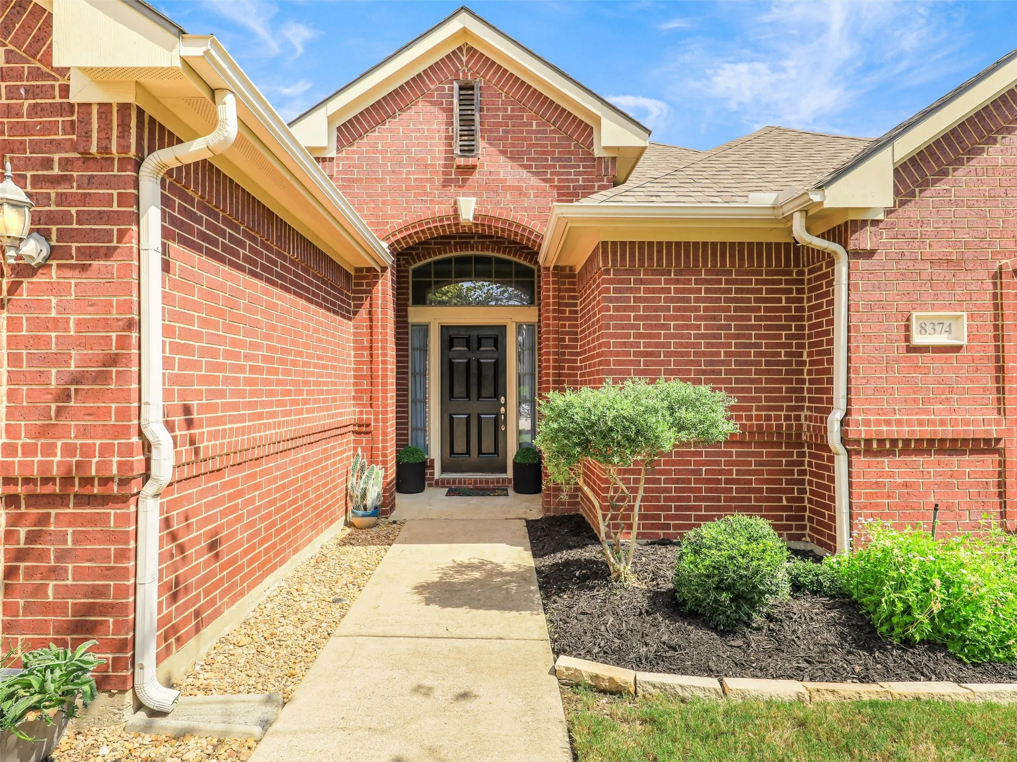Covered front entry features door with side lights and a transom window for extra light and a landscaped walkway.