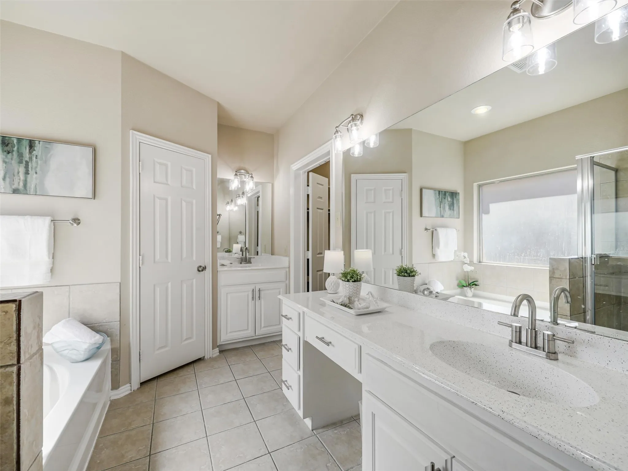 White vanity cabinetry, generous counter space, and large mirrors create a bright and functional space for daily routines.