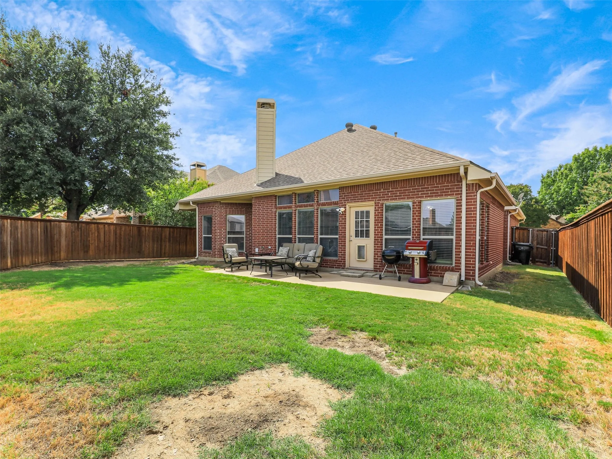 Enjoy outdoor gatherings on the backyard patio, with direct access to the home and an open lawn enclosed by wood fencing.