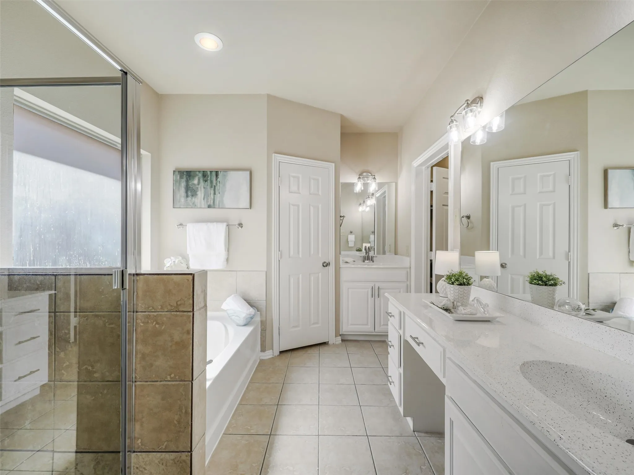 Primary bathroom features two vanity areas, a separate glass-enclosed shower, a soaking tub, and tile flooring.