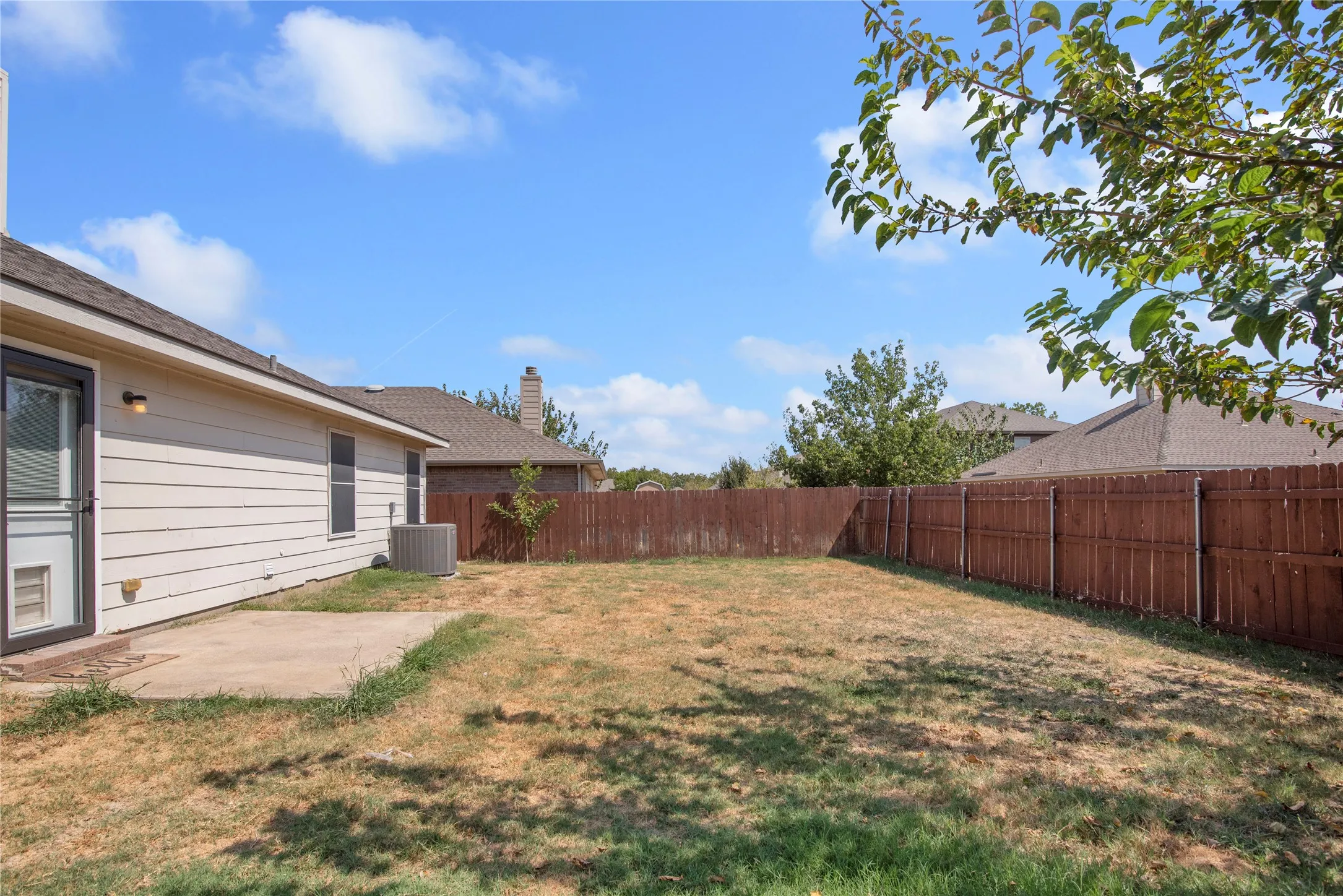 Expansive backyard with a full privacy fence and a concrete patio