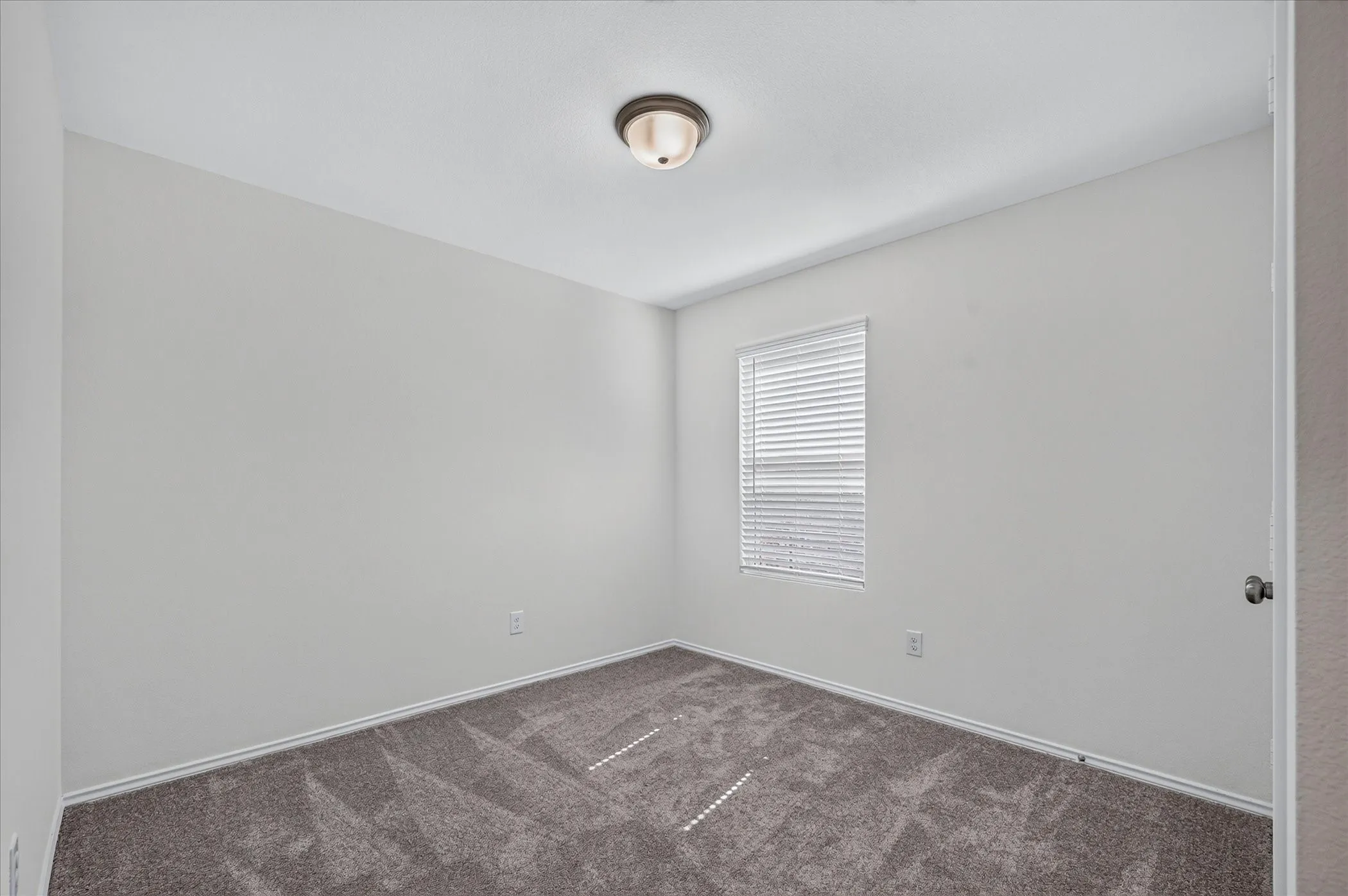 Window with blinds, wall-to-wall carpeting, and a flush mount ceiling light fixture