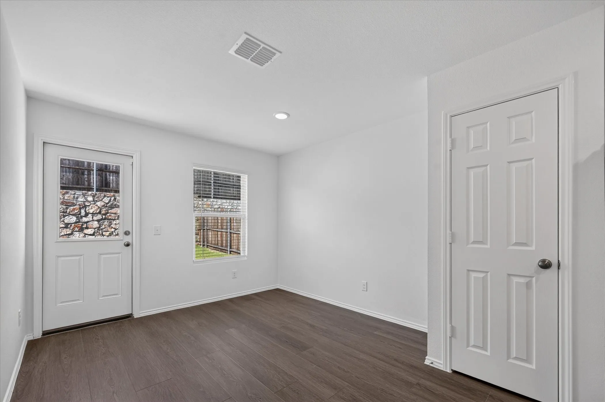 Recessed lighting, wood-finish flooring, white walls, white trim, and a paneled interior door