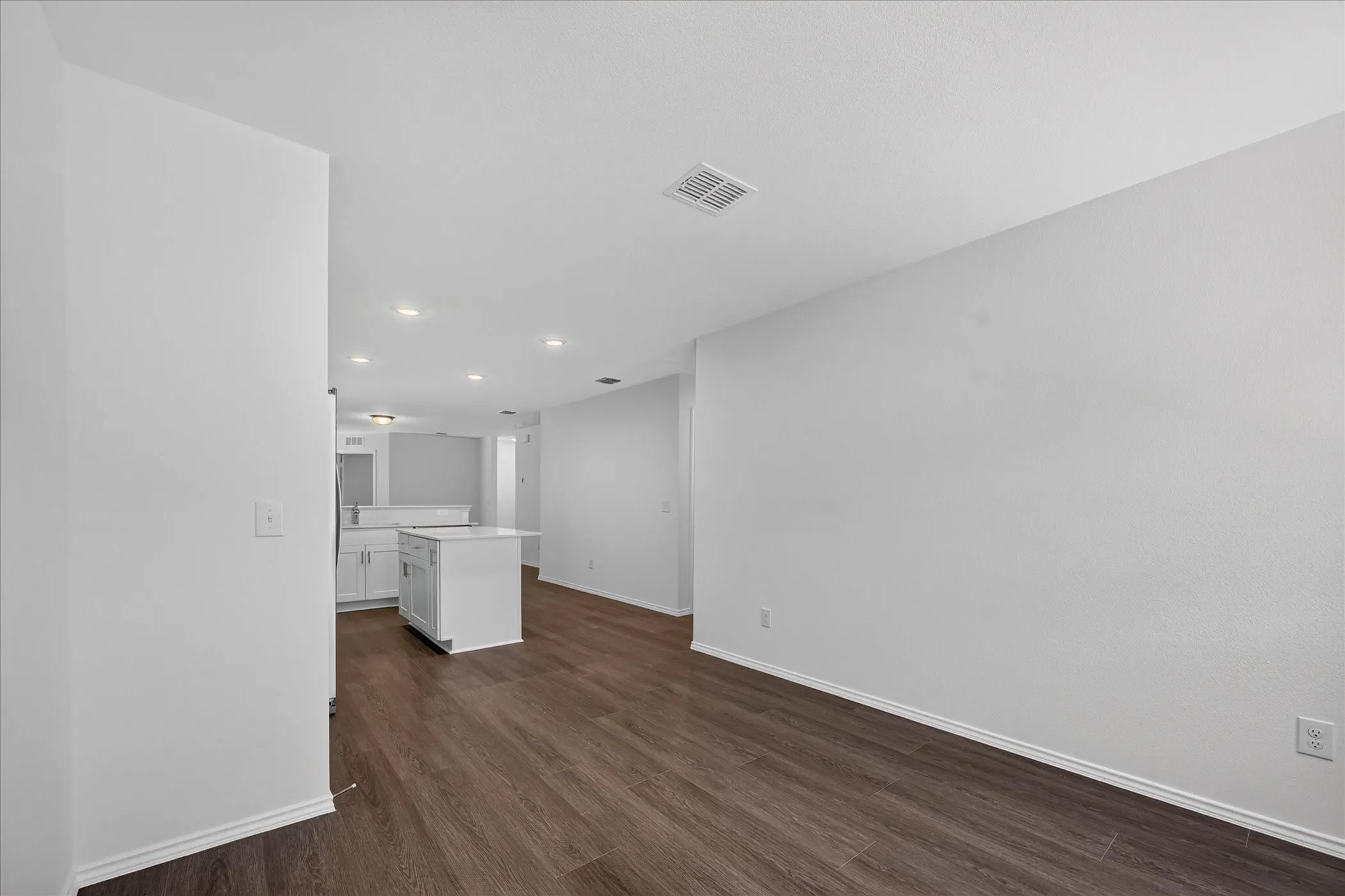 Open-concept living area with wood-finish flooring, recessed lighting, and white walls