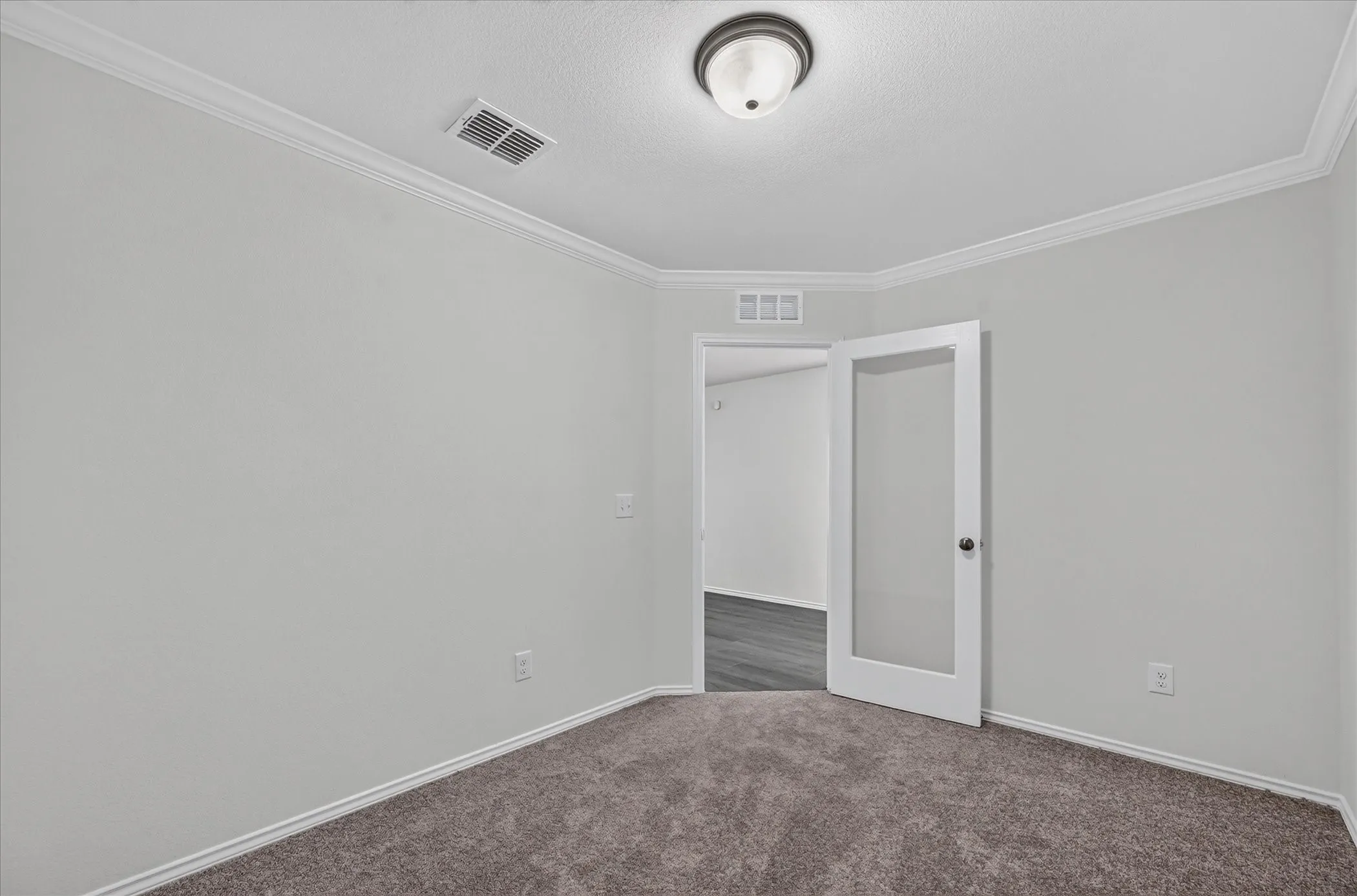 Gray carpet flooring with crown molding and a semi-flush mount ceiling light