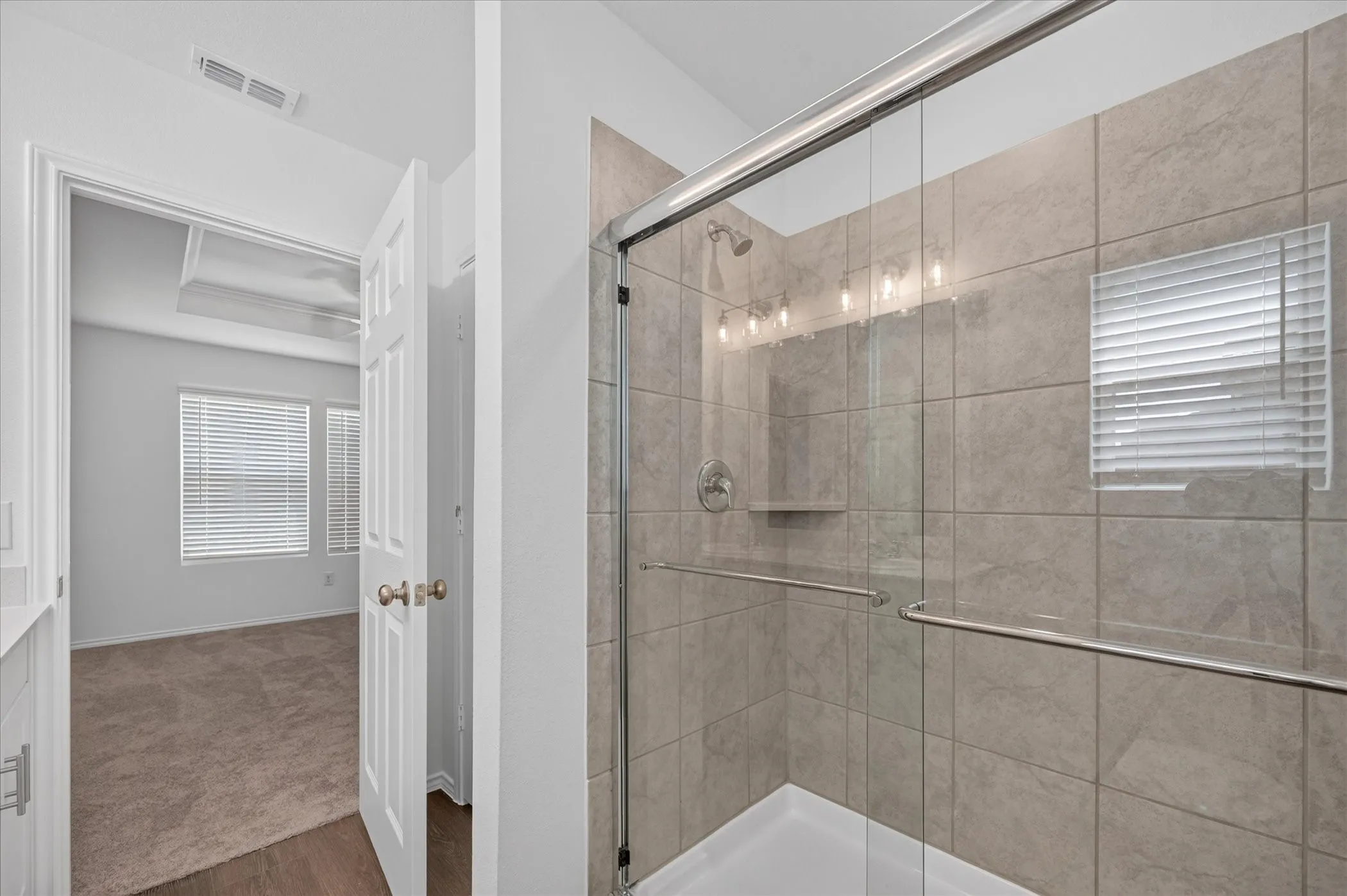 Glass-enclosed shower with tiled walls and a built-in shelf