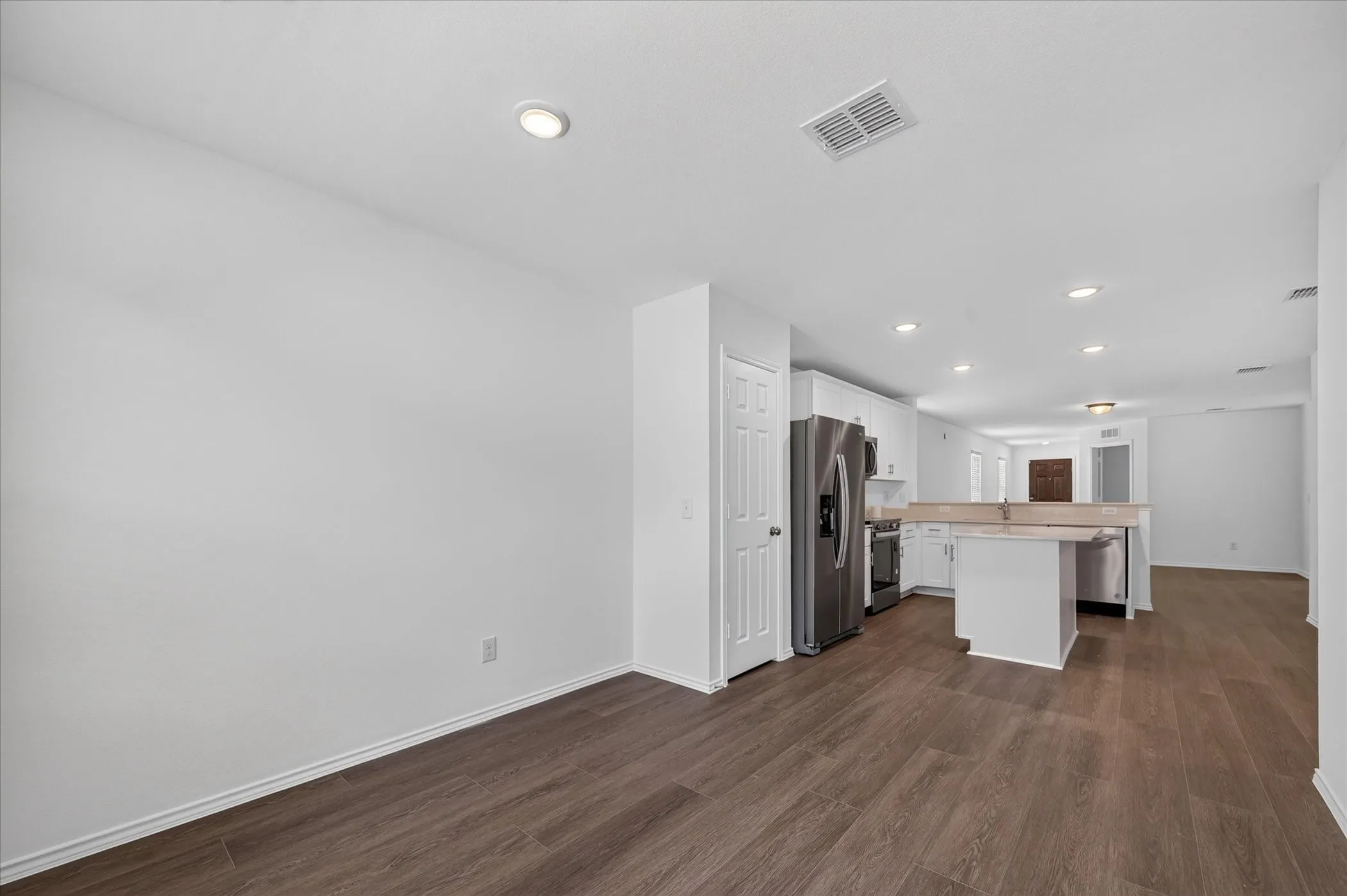 Open-concept living space with wood-finish flooring, recessed lighting, and a kitchen island with seating