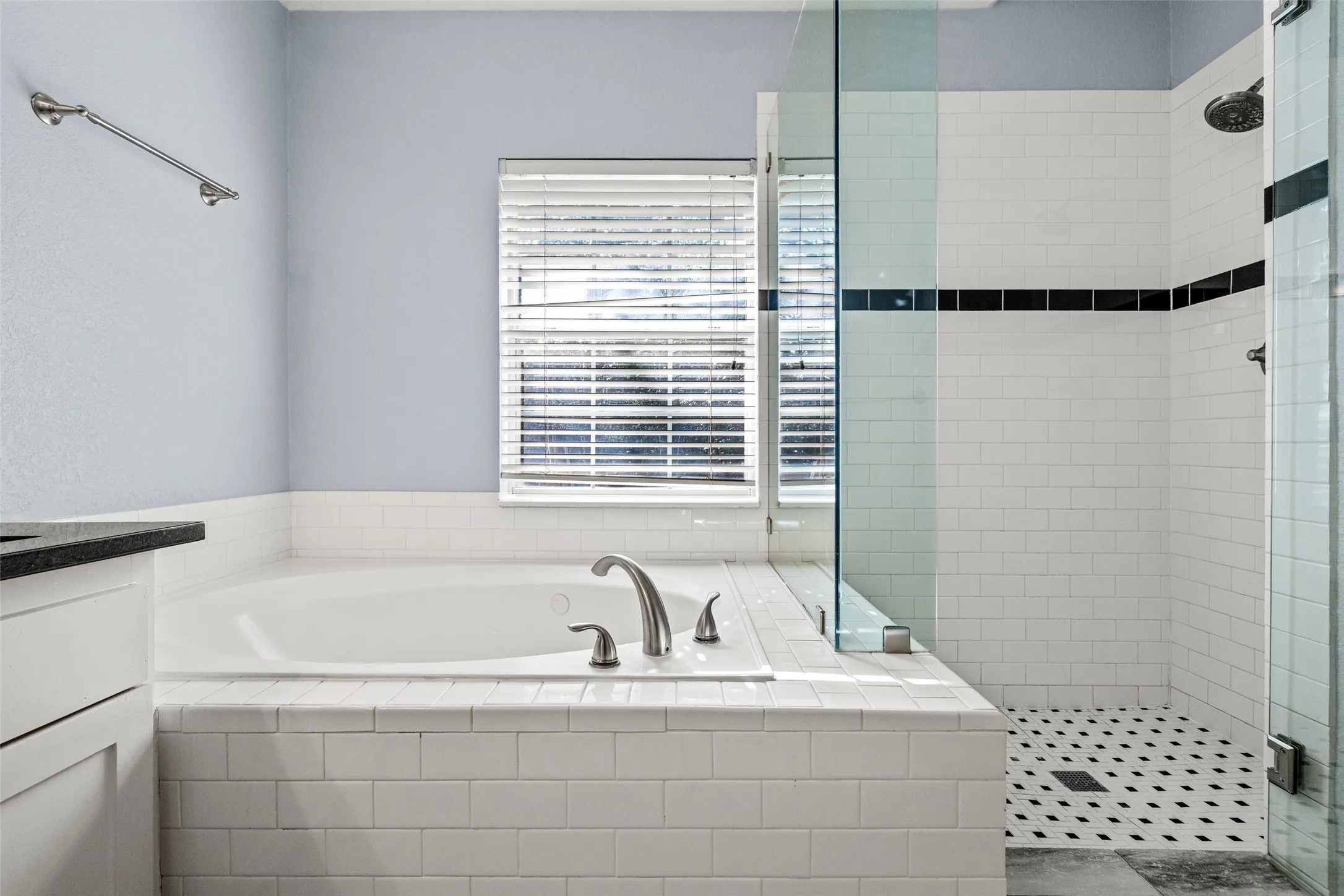 Deep soaking tub with brushed nickel fixtures, white subway tile surround, and a clear glass shower enclosure