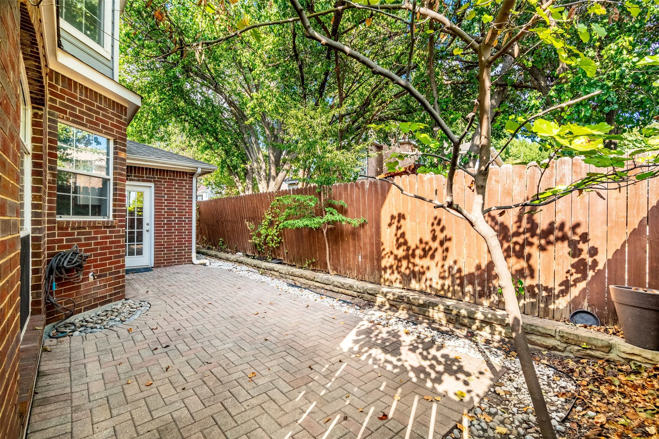Brick exterior construction with white window frames, a white multi-pane glass door, and a paver patio