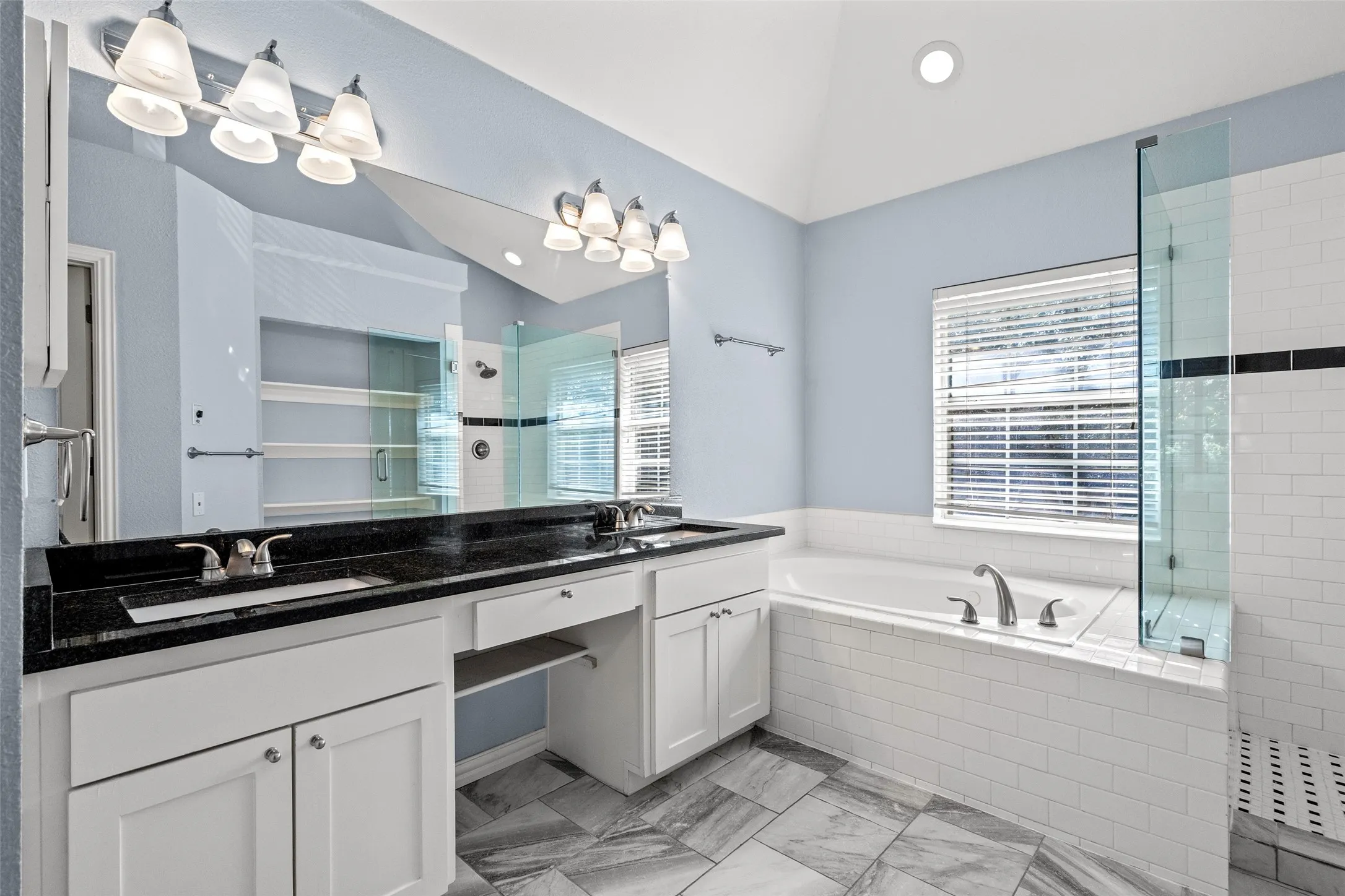 Dual vanity with undermount sinks, black countertop, and white cabinetry