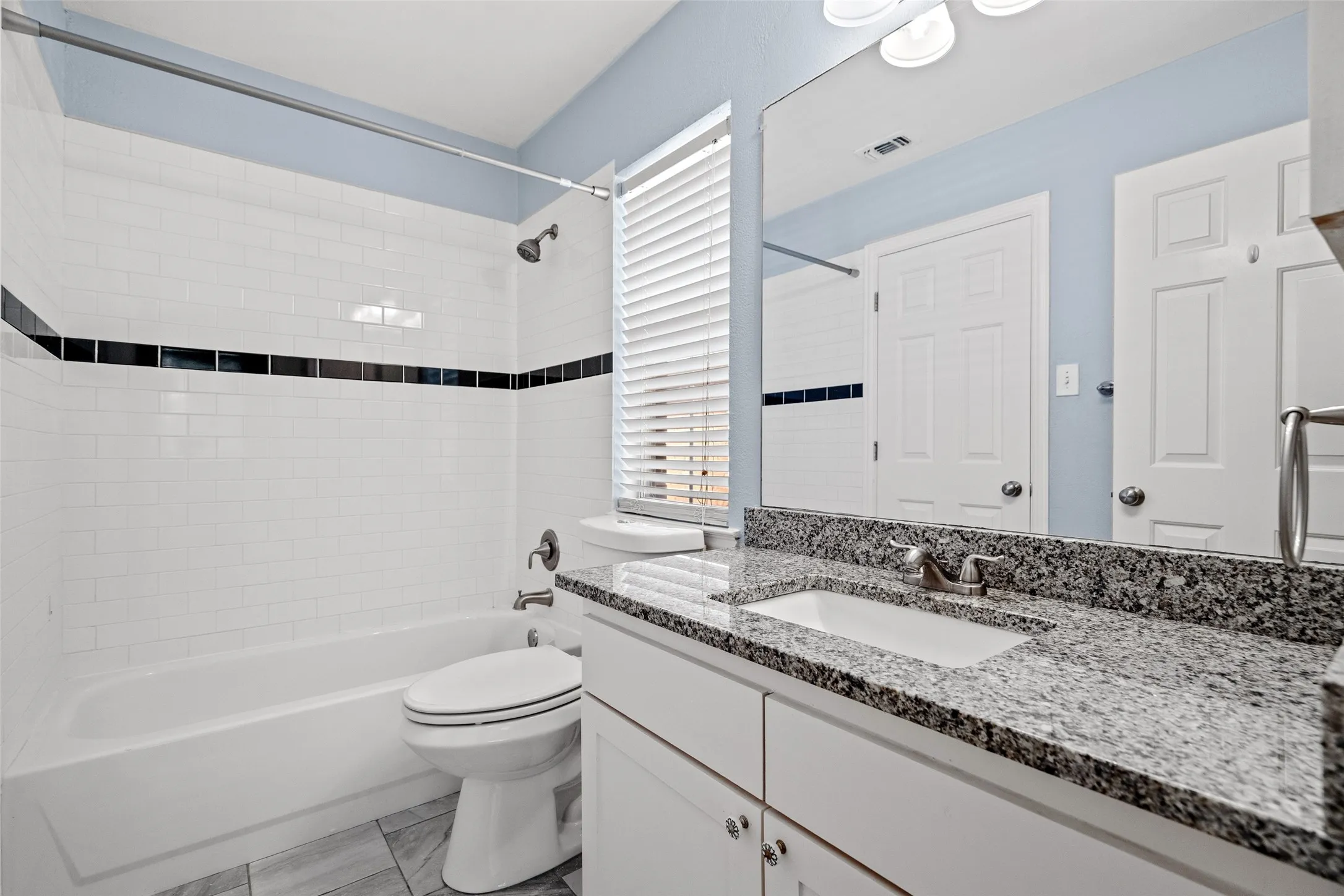 White subway tile shower surround with a black accent band