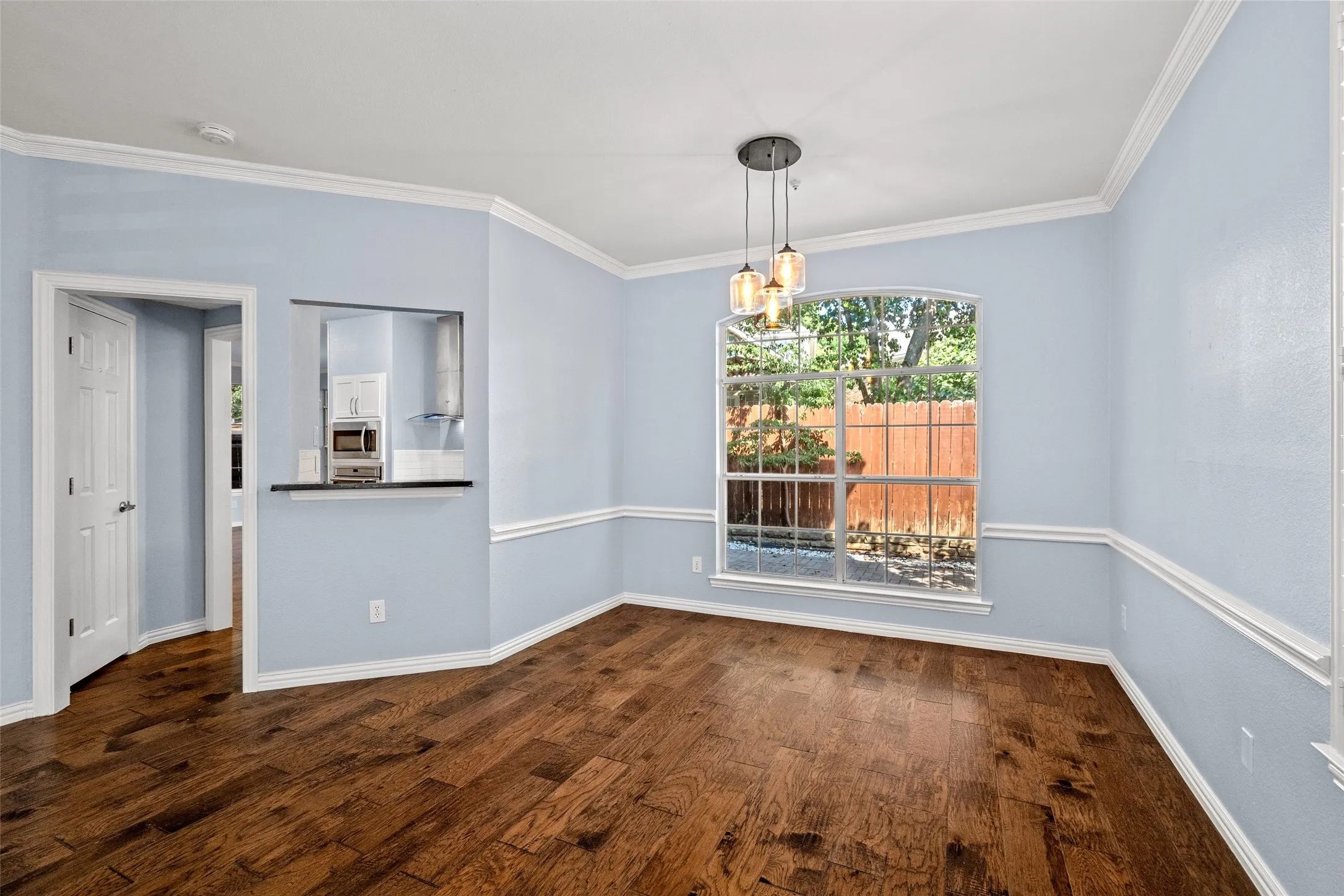 Wood-finish flooring with crown molding and chair rail accents
