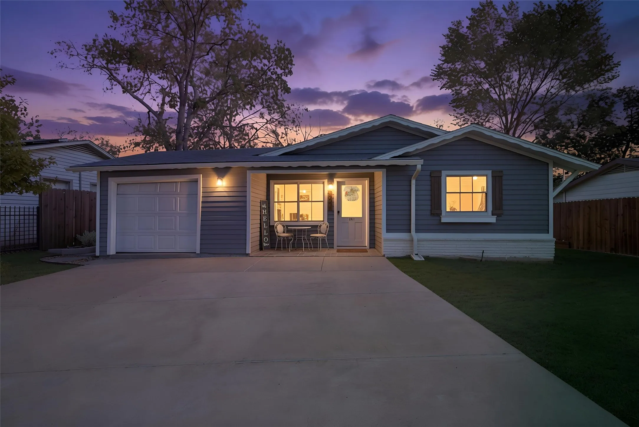Exterior featuring horizontal siding, attached garage, front porch, and mature trees