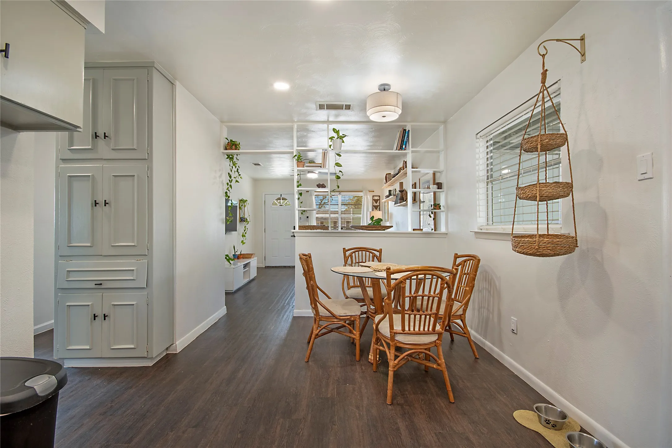 Wood-finish flooring, built-in shelving, recessed lighting, and a white framed window with blinds