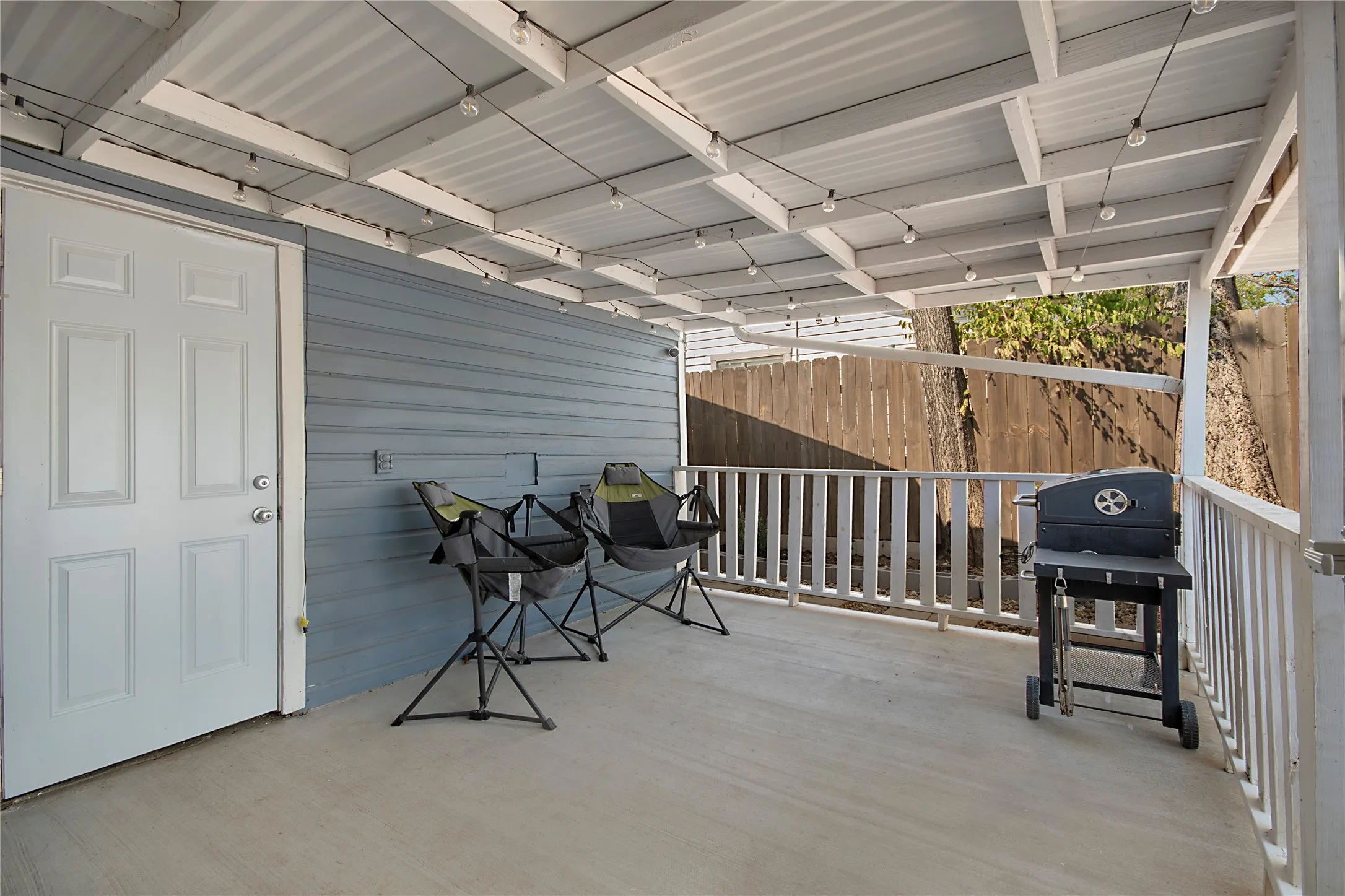 Covered patio with a concrete floor, white railing, and paneled exterior siding