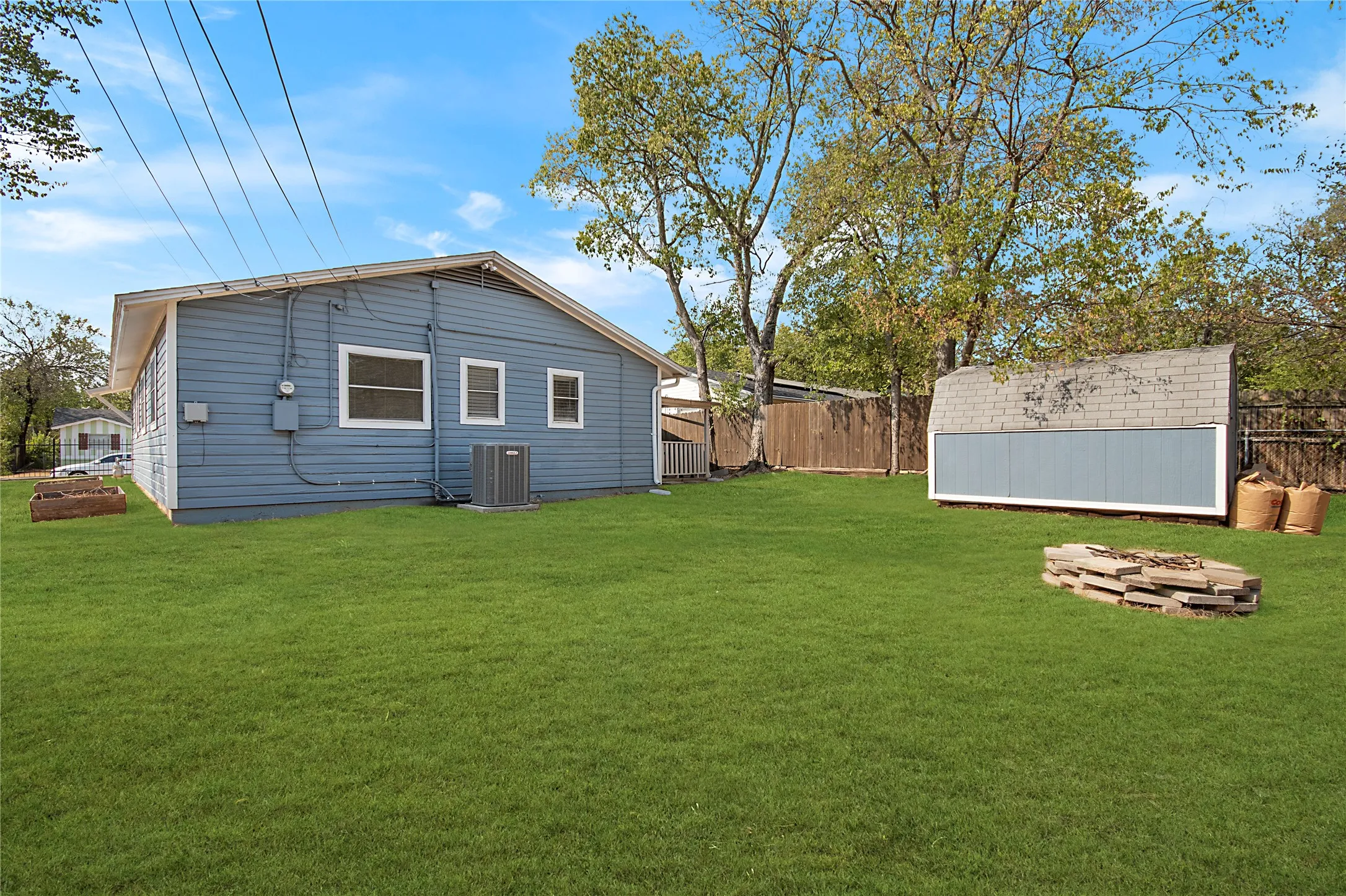Expansive green lawn, detached storage structure, mature trees, and privacy fencing