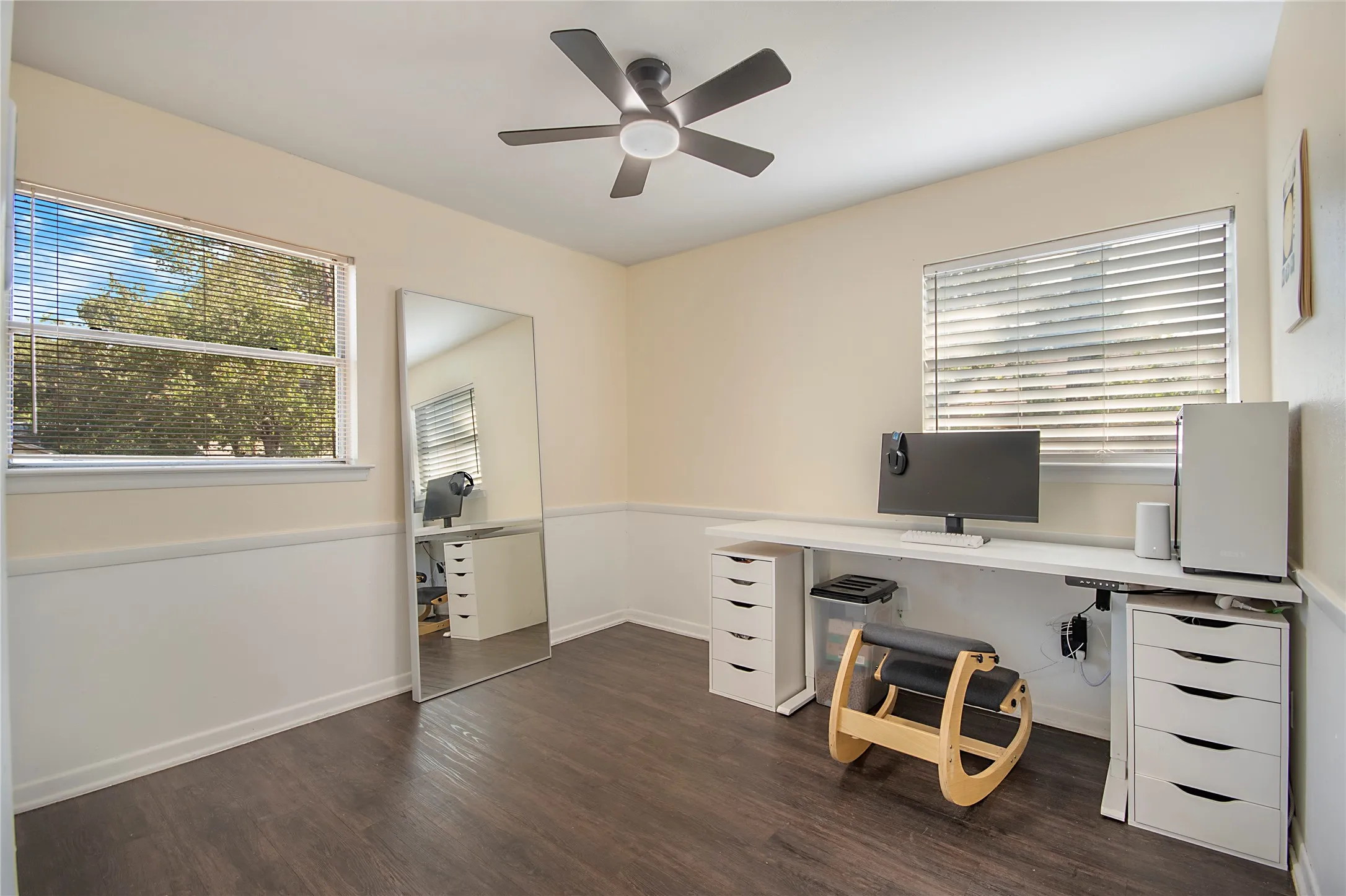 Ceiling fan, two windows with blinds, wood-finish flooring, and chair rail molding