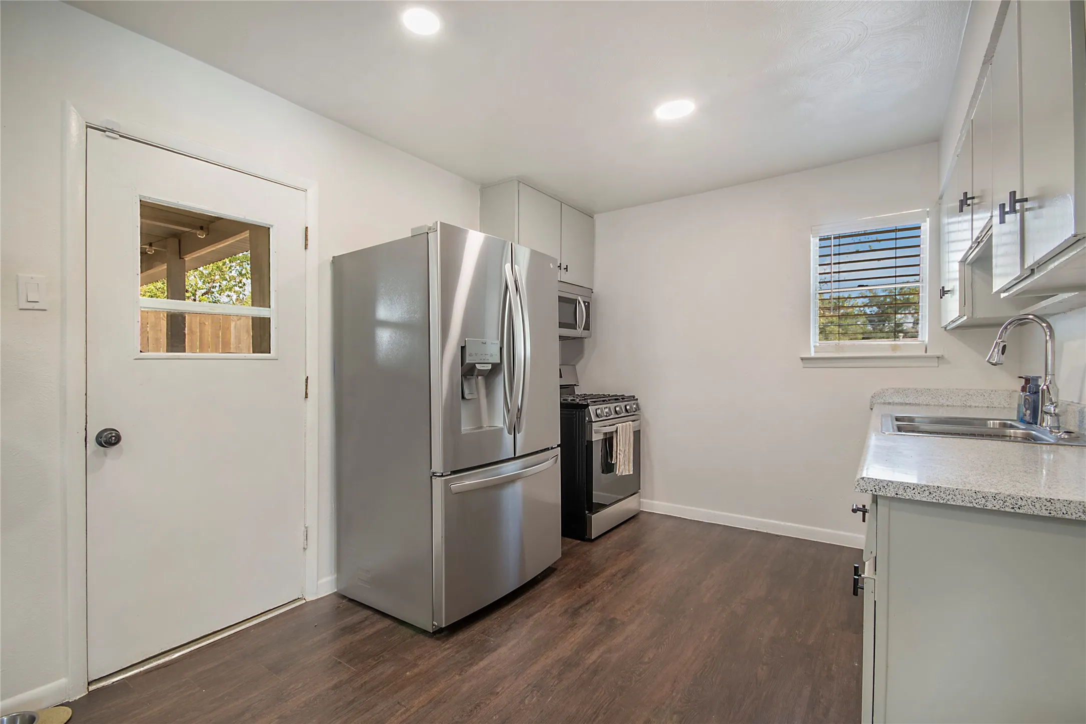 Kitchen featuring wood-finish flooring, recessed lighting, stainless steel appliances, stone countertops, and light-toned cabinetry