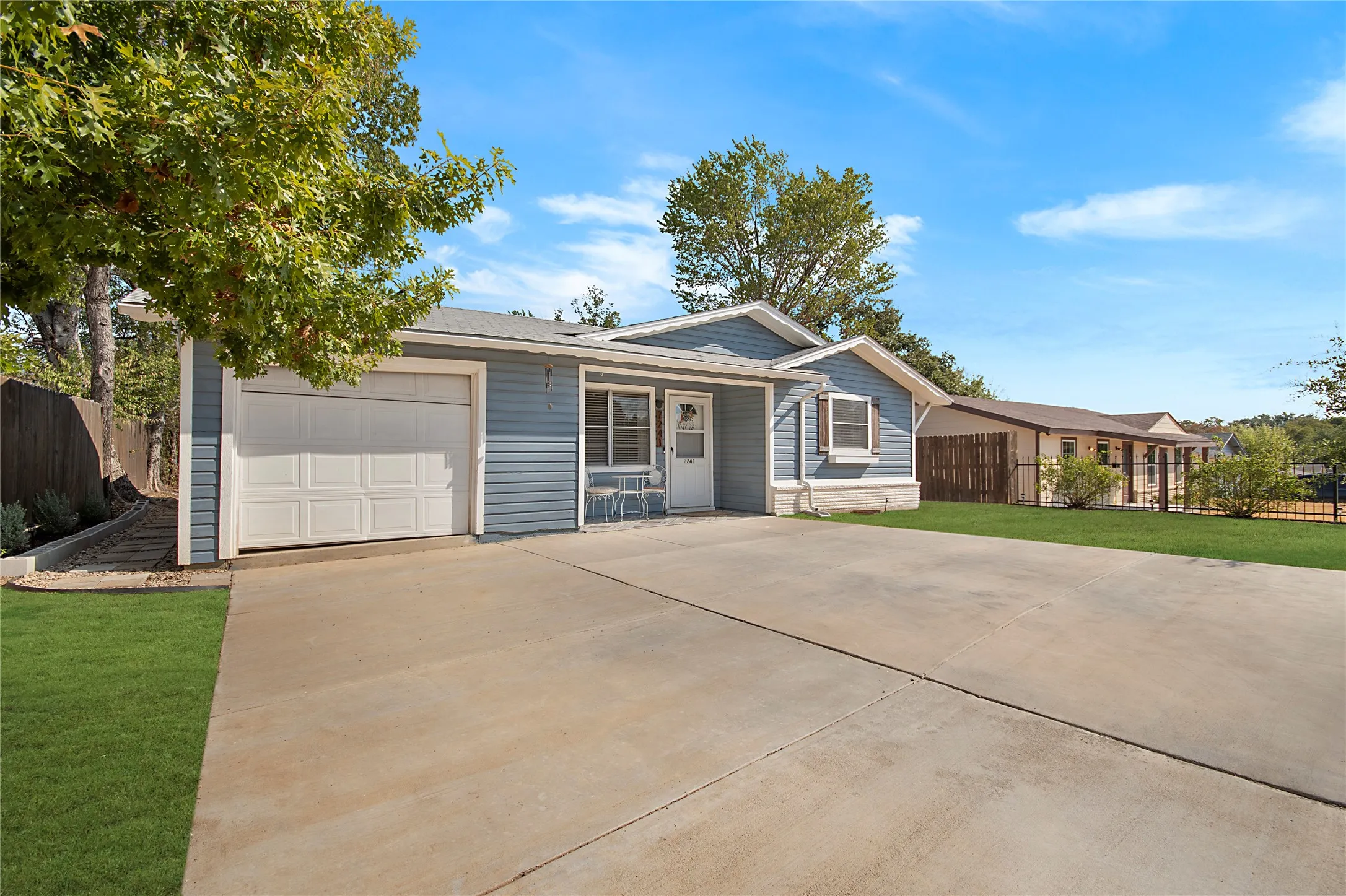 Single-story residence featuring light blue siding, an attached garage, and a concrete driveway