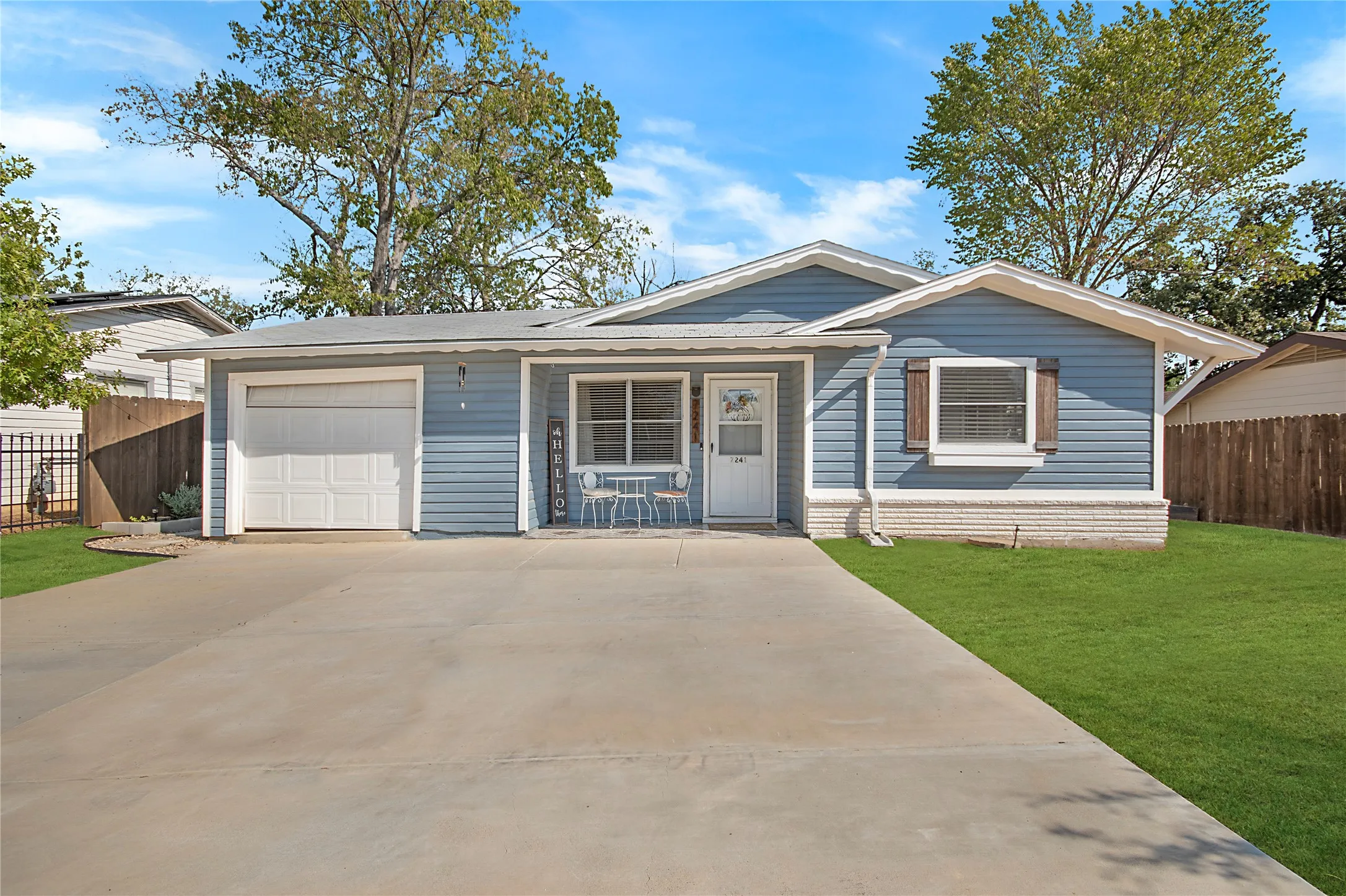 Light blue siding exterior with white trim, featuring a single-car garage and a concrete driveway