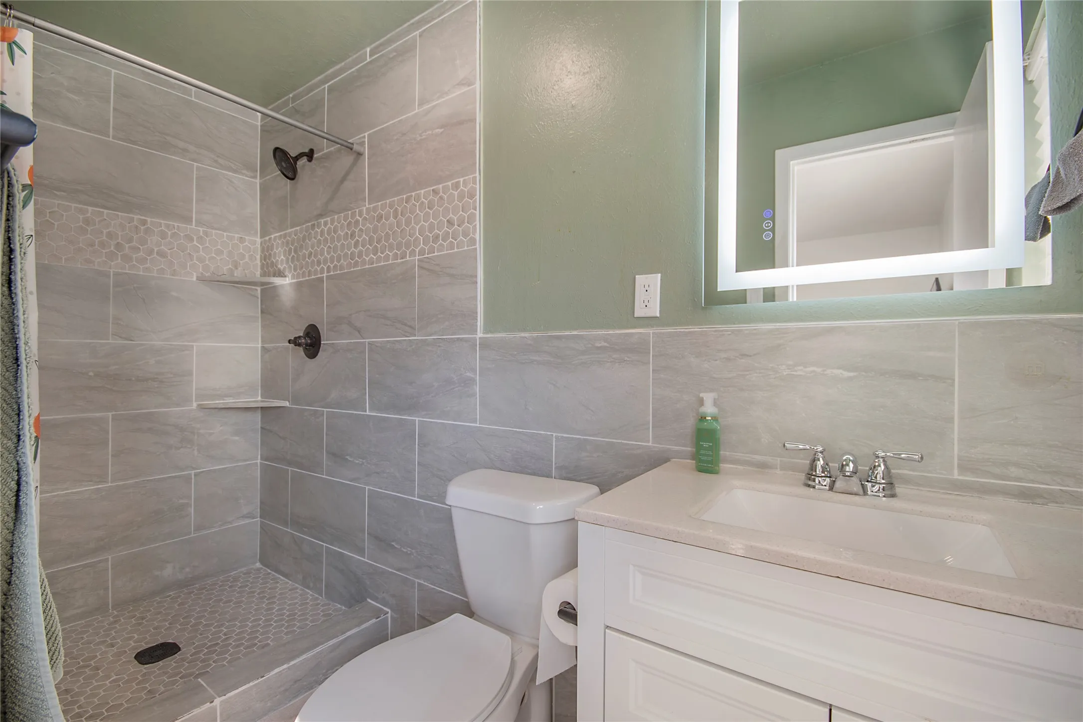 Tiled shower with built-in shelving, penny tile shower pan, and dark bronze fixtures