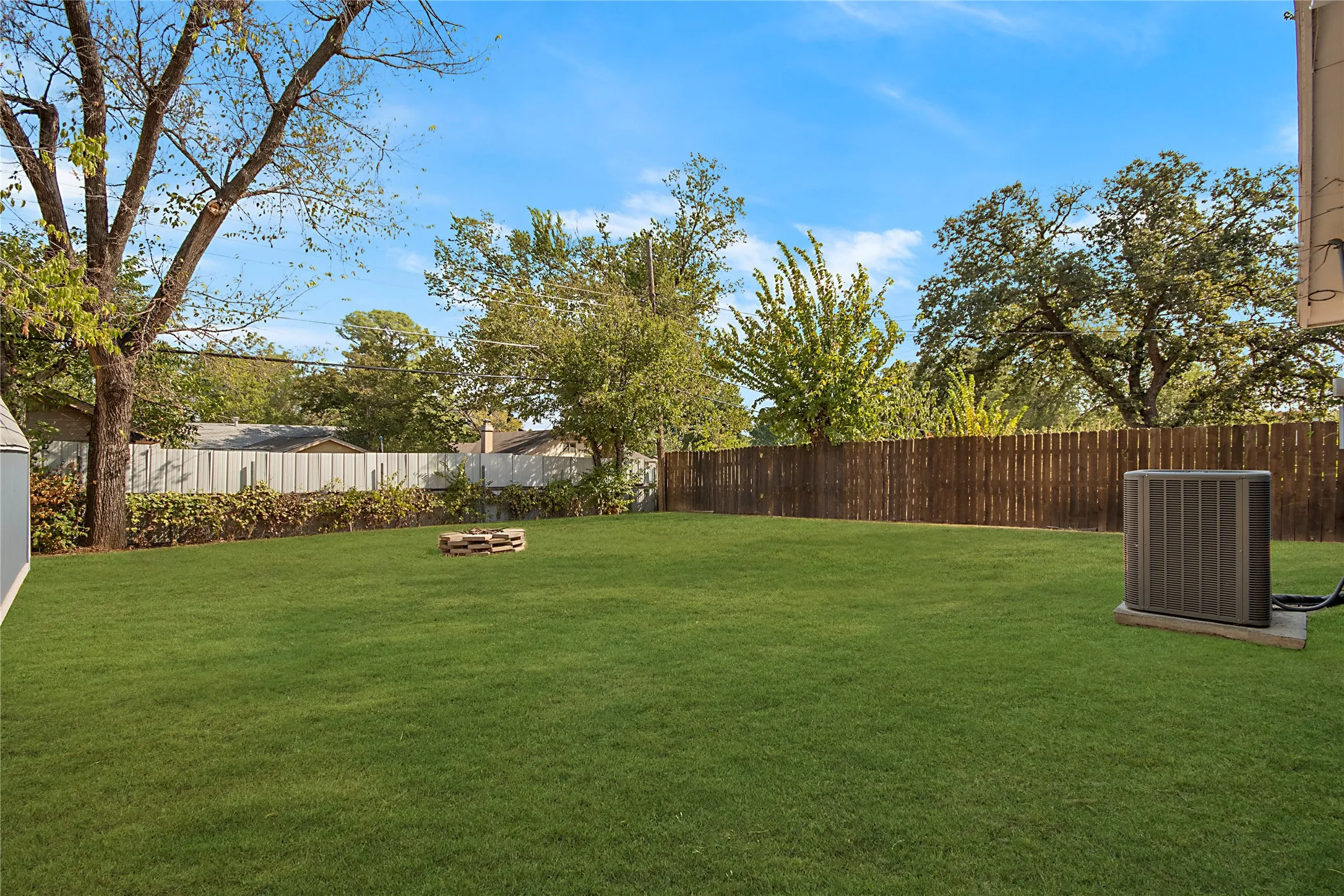 Expansive backyard with a lush lawn, mature trees, and privacy fencing