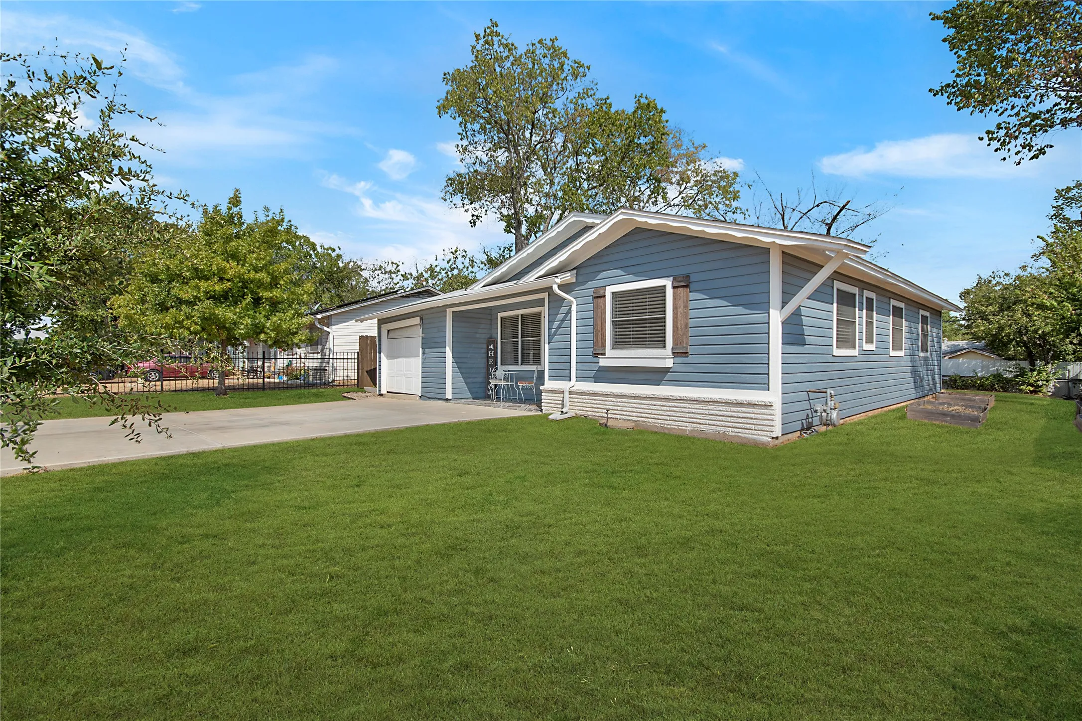 Single-story residence featuring blue siding, white trim, and a concrete driveway