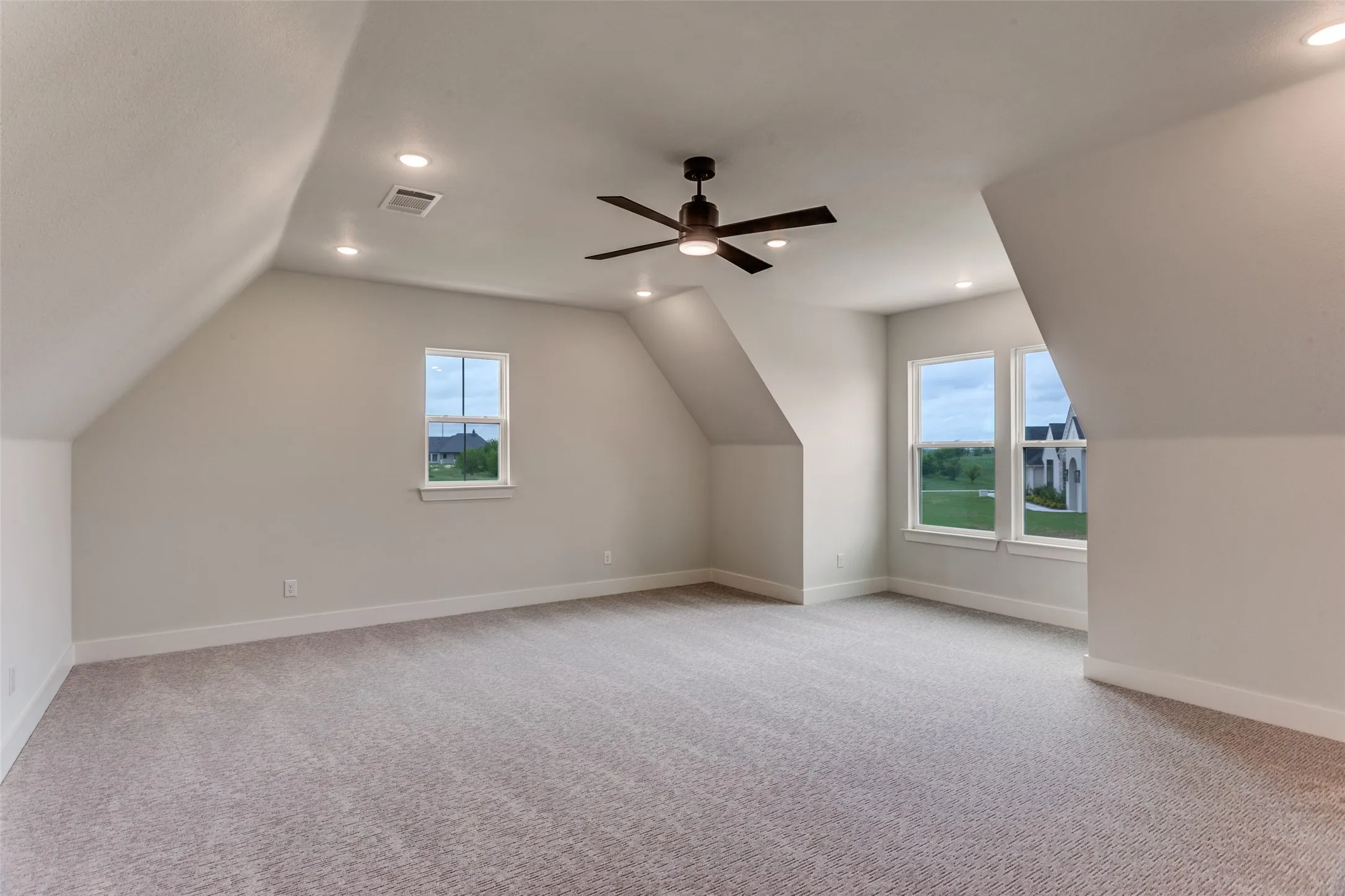 Spacious room with sloped ceilings, recessed lighting, and a ceiling fan