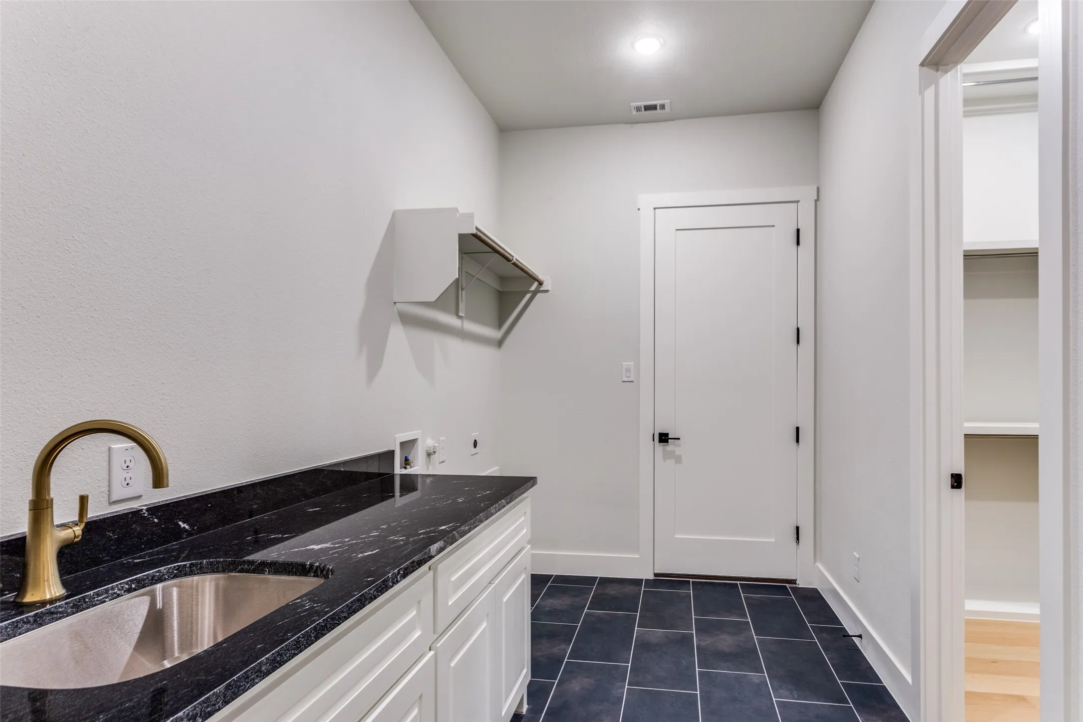Dark stone countertop with an undermount sink and brass-finish faucet
