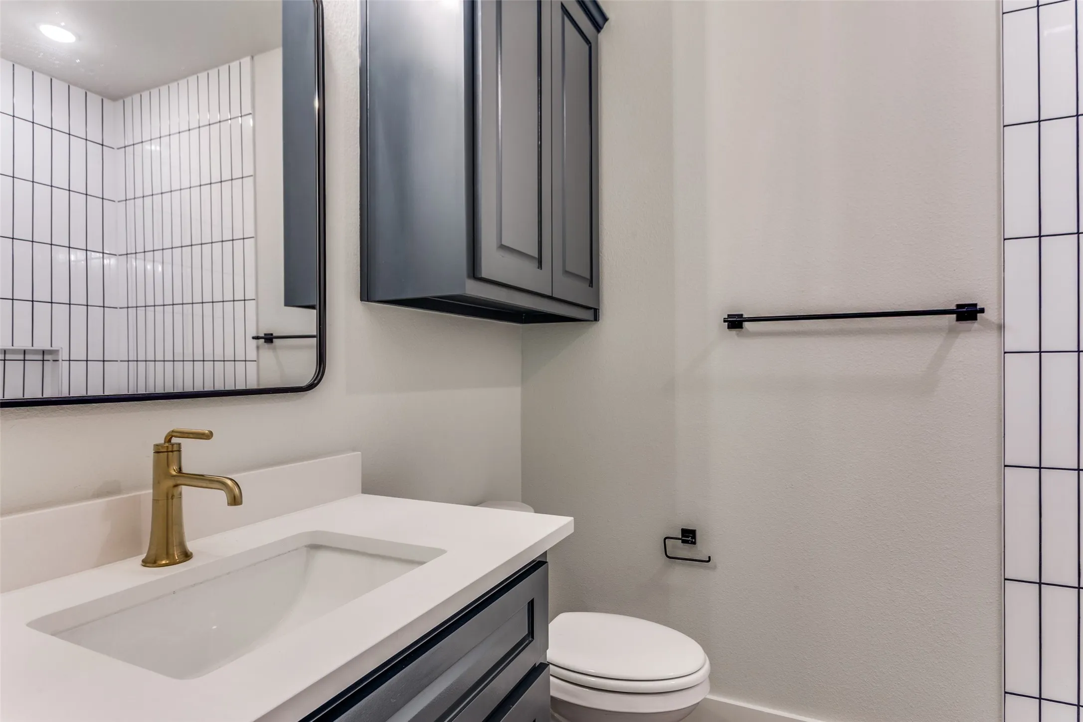 Vanity with white countertop, integrated rectangular sink, and brass-tone faucet