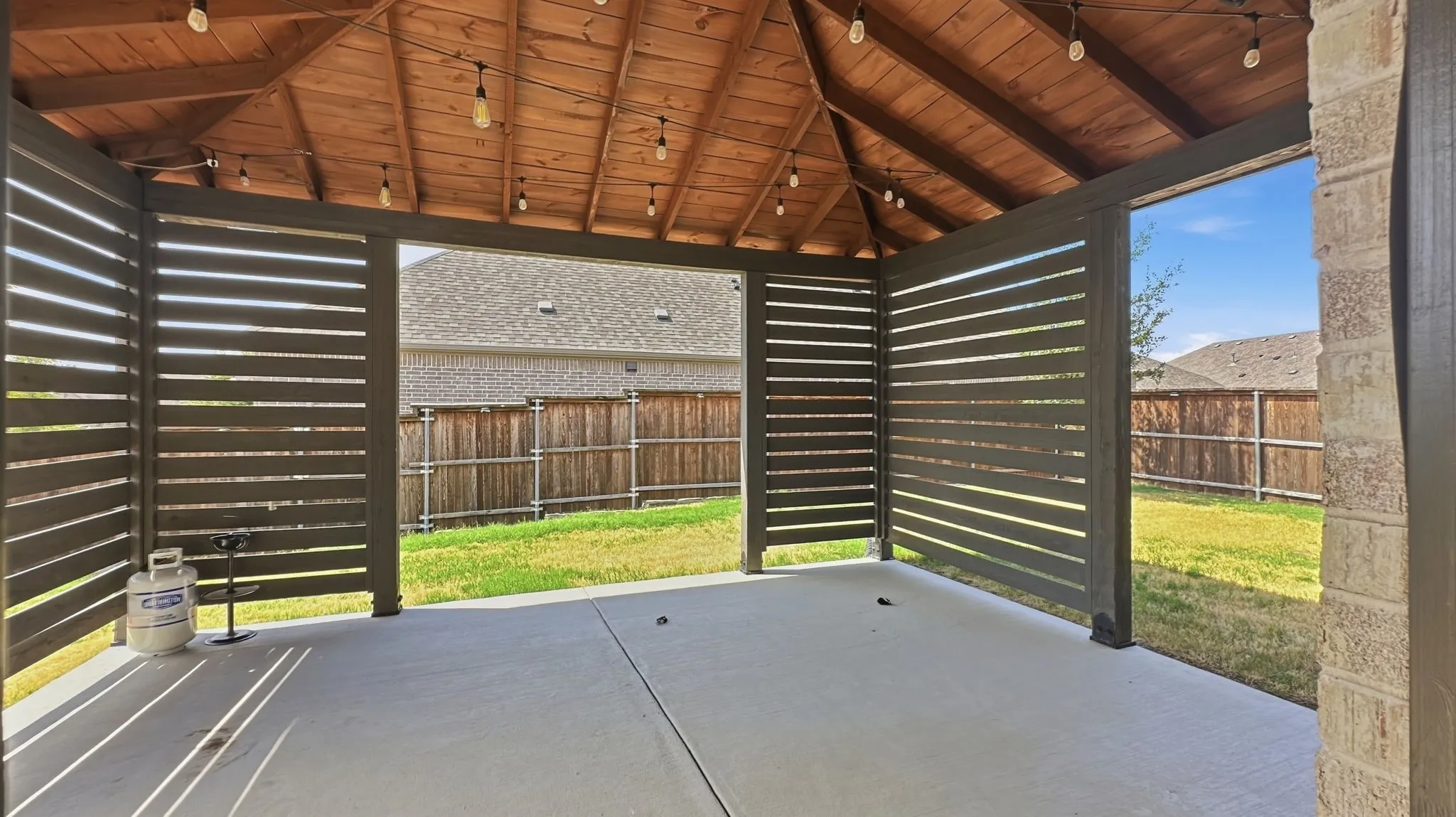 Covered patio featuring a wood-finish vaulted ceiling and concrete flooring