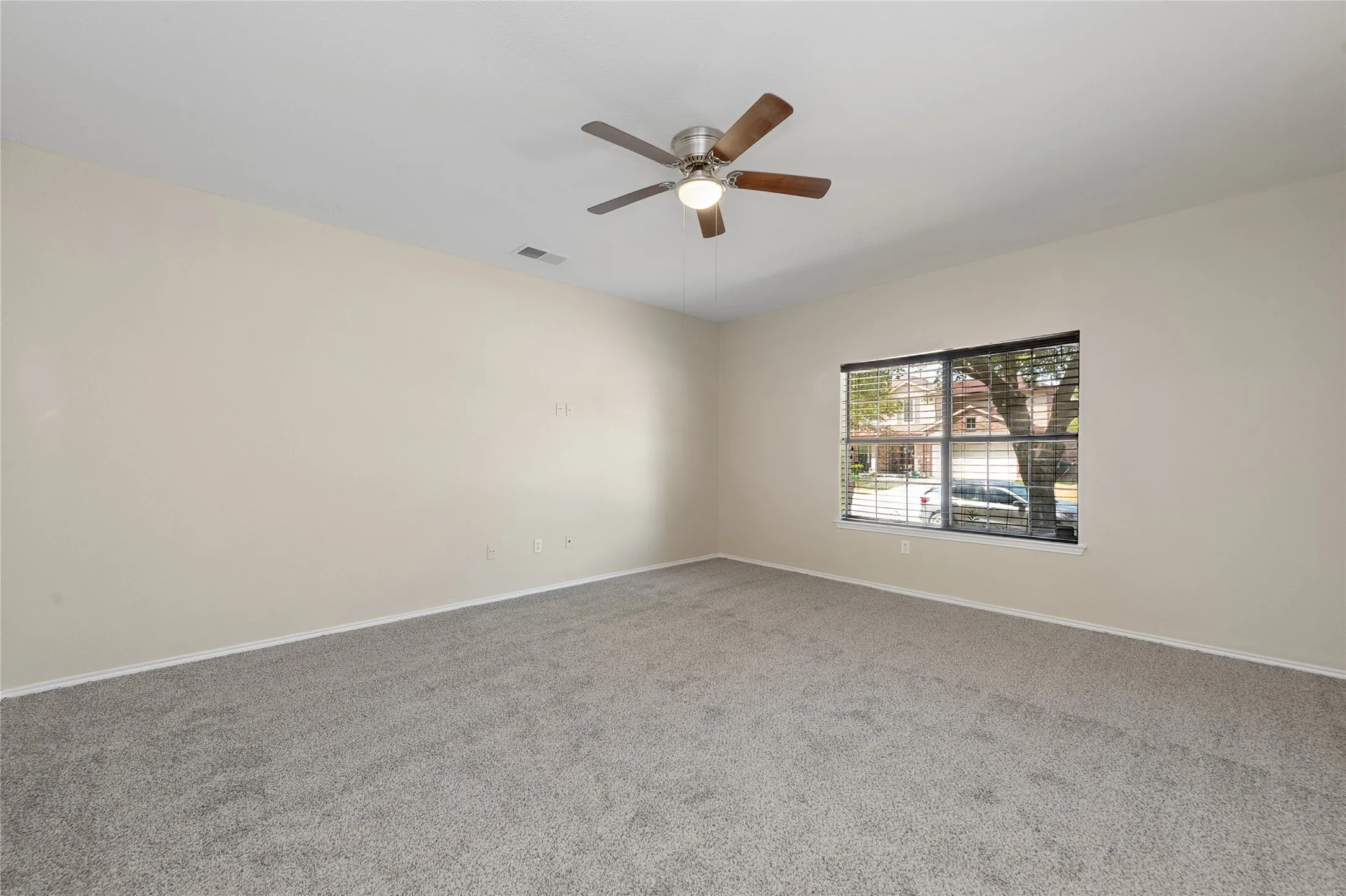 Spacious room featuring neutral carpeting and a ceiling fan with integrated lighting