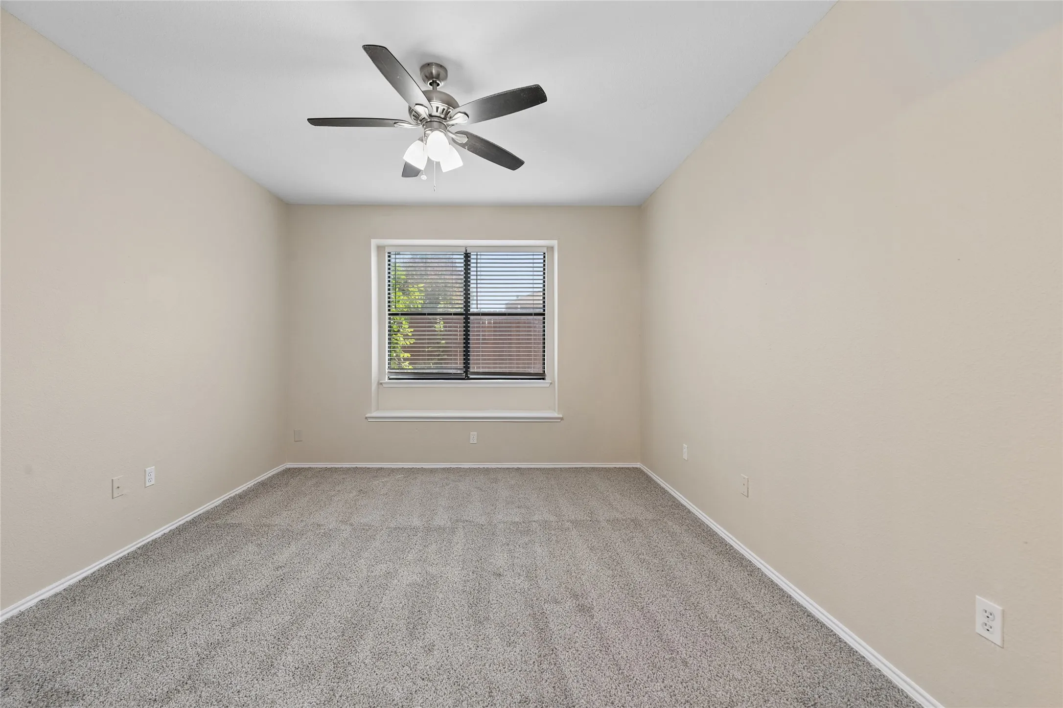 Neutral-toned walls with grey carpeting and a ceiling fan with integrated lighting