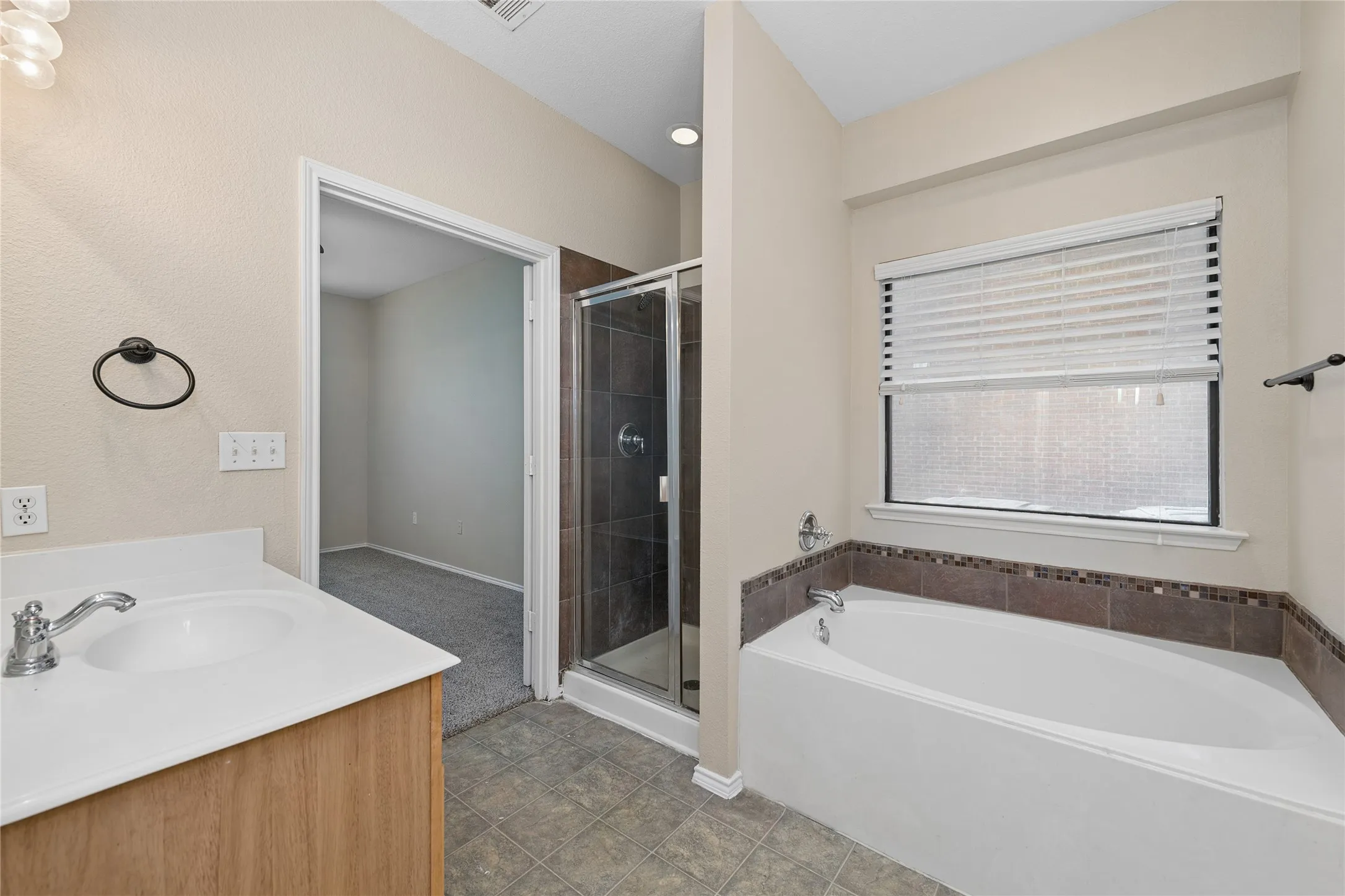 Bathroom featuring a single vanity, built-in bathtub with tile surround, and an enclosed shower with glass door