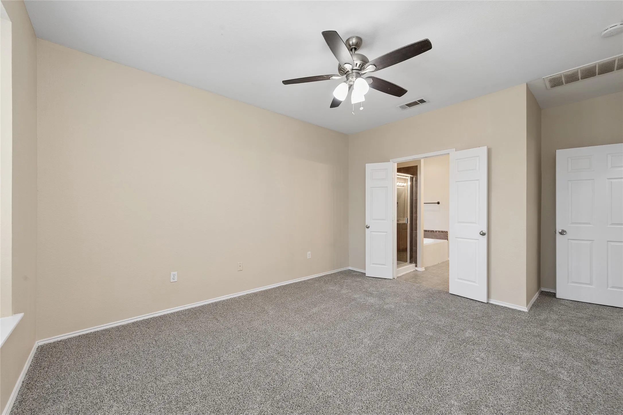 Neutral-toned walls, gray carpet flooring, and a ceiling fan with integrated lighting