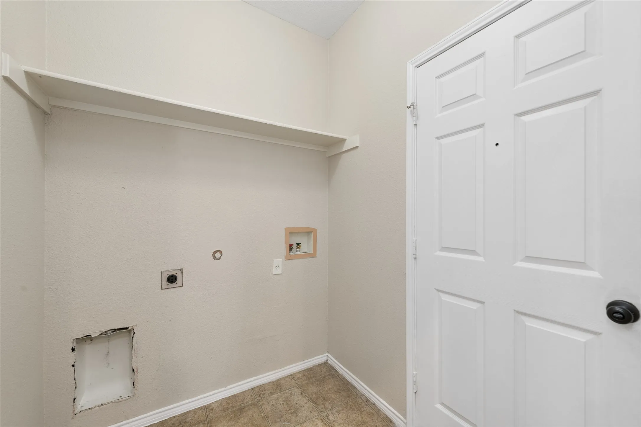 Utility area featuring a built-in shelf, neutral wall color, and a paneled door with dark hardware
