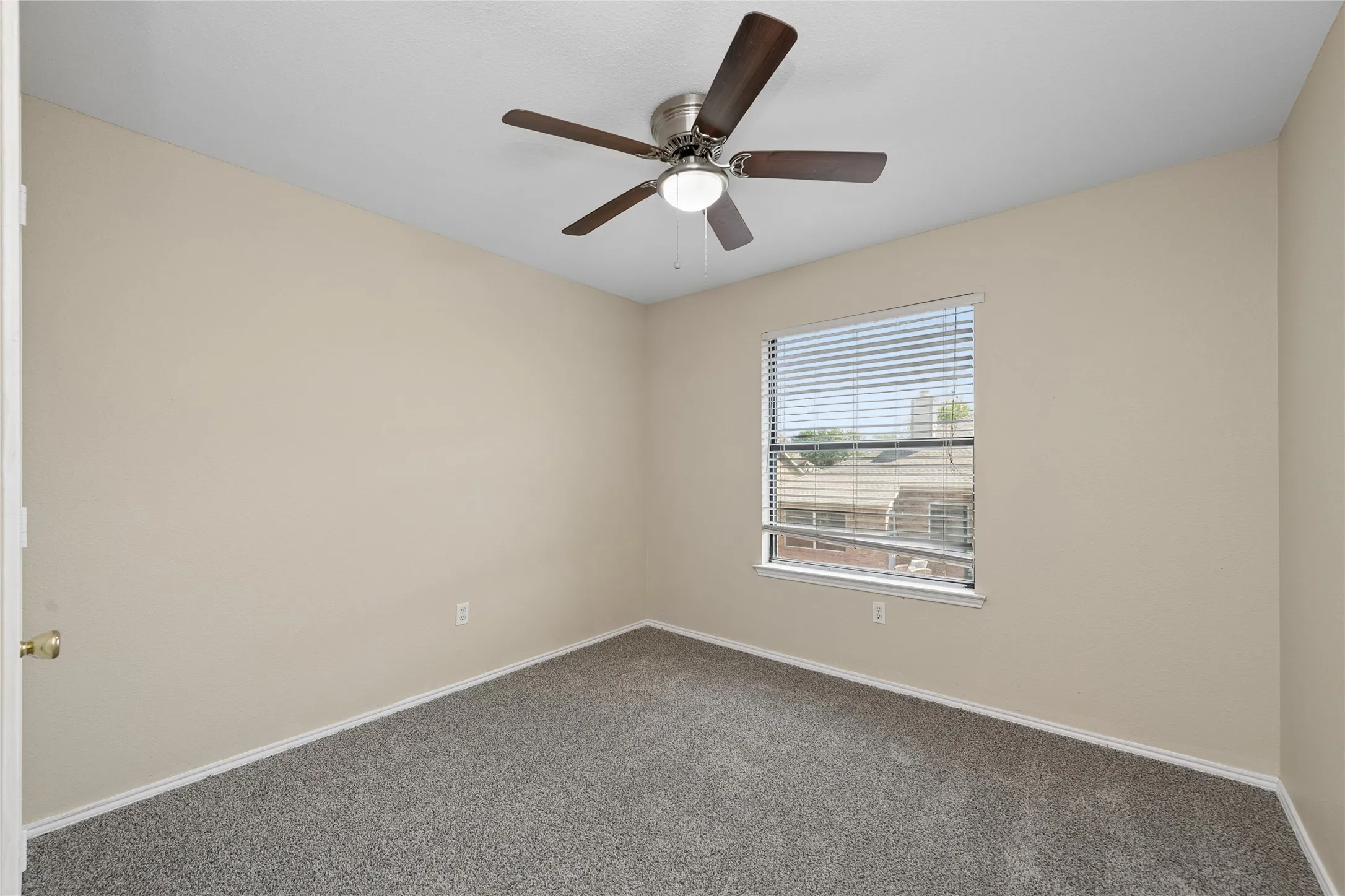 Neutral wall tones, ceiling fan with integrated lighting, window with blinds, and grey carpeting