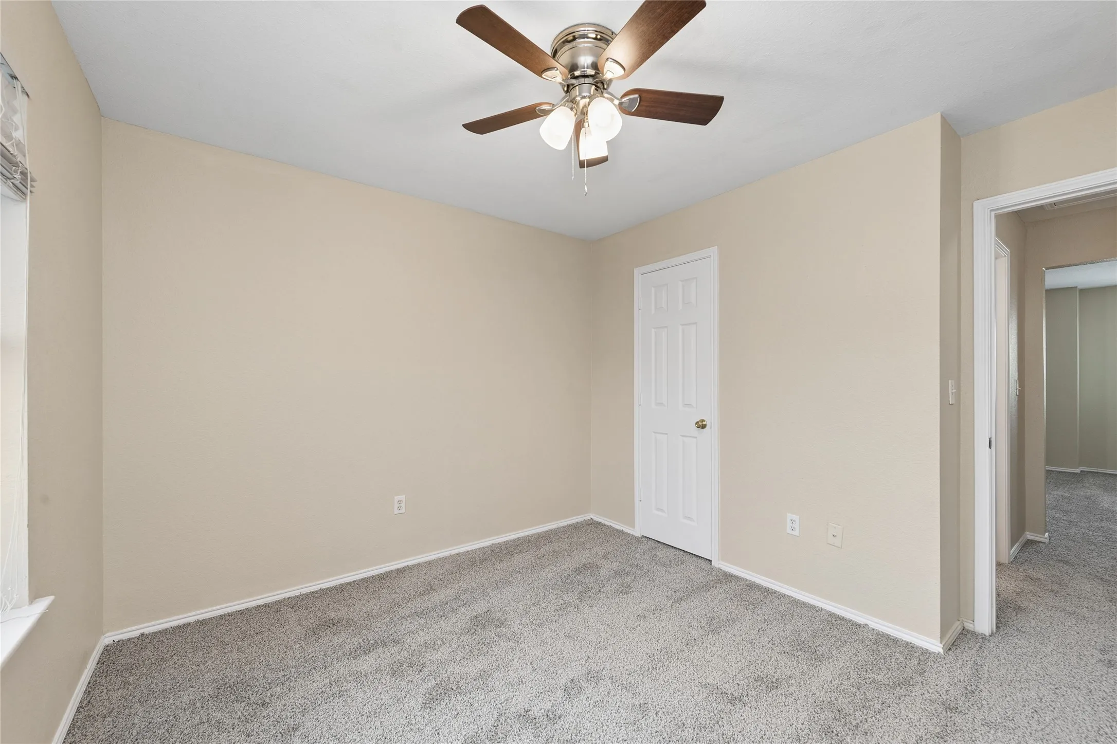 Neutral tone wall paint, carpeted flooring, white trim, ceiling fan with light, and a white paneled door