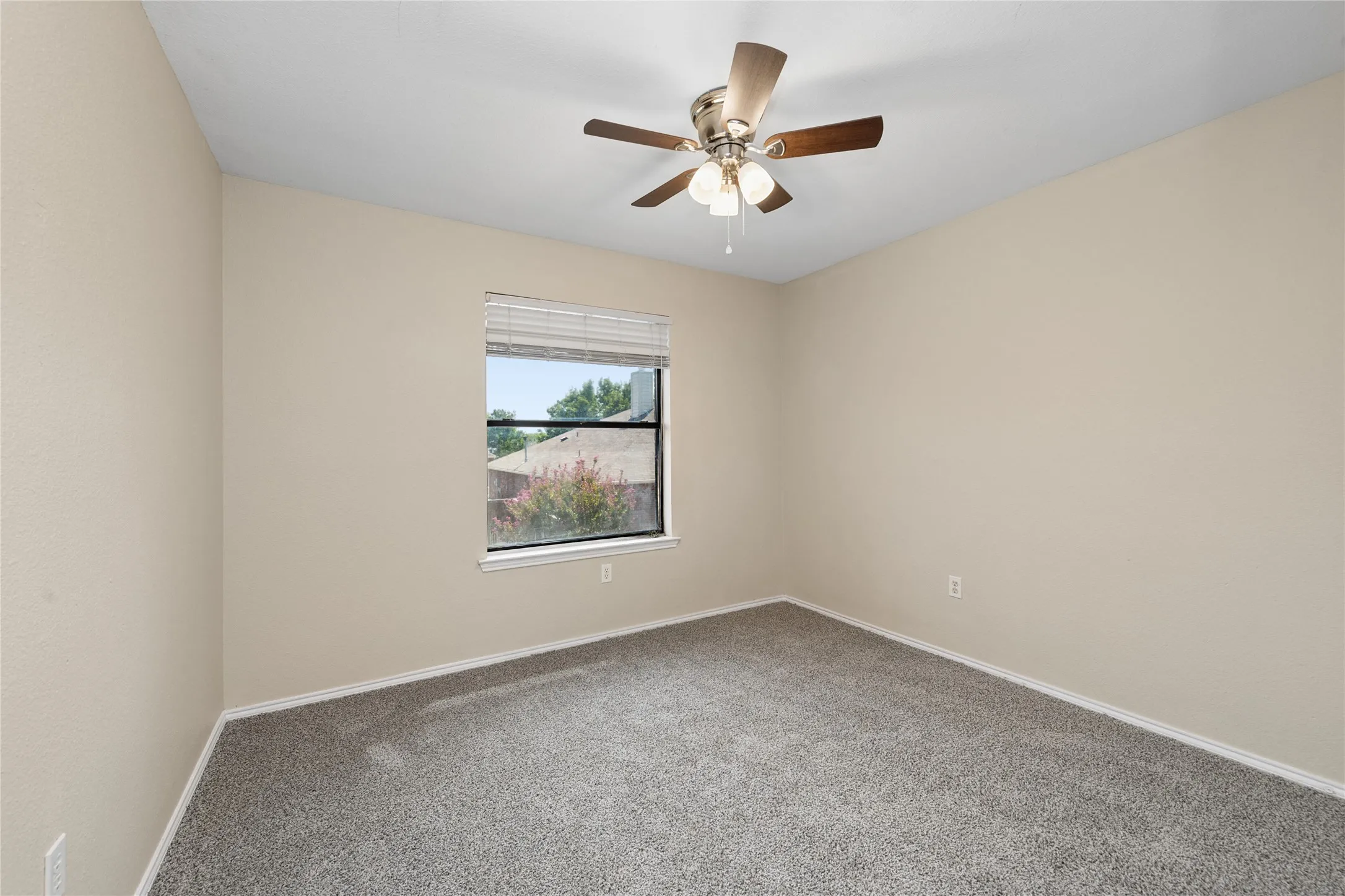 Light beige wall paint, gray carpeting, window with blinds, and a ceiling fan with light fixture