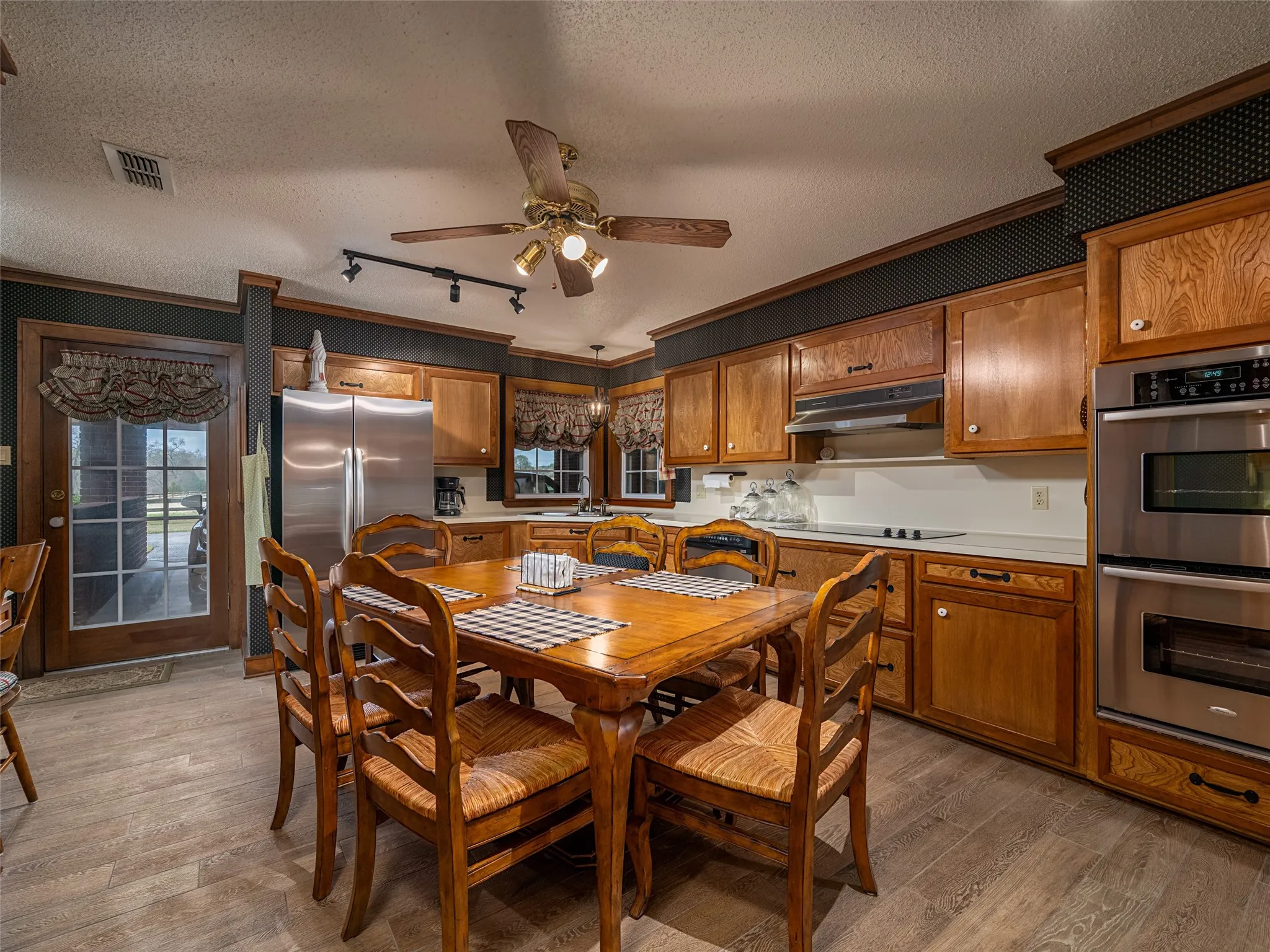 Kitchen featuring wood-finish cabinetry, stainless steel double wall ovens, a built-in cooktop, and light-toned countertops