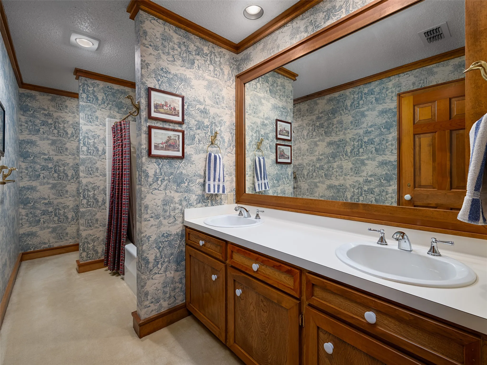 Double vanity with integrated sinks, wood cabinetry, large framed mirror, and recessed lighting