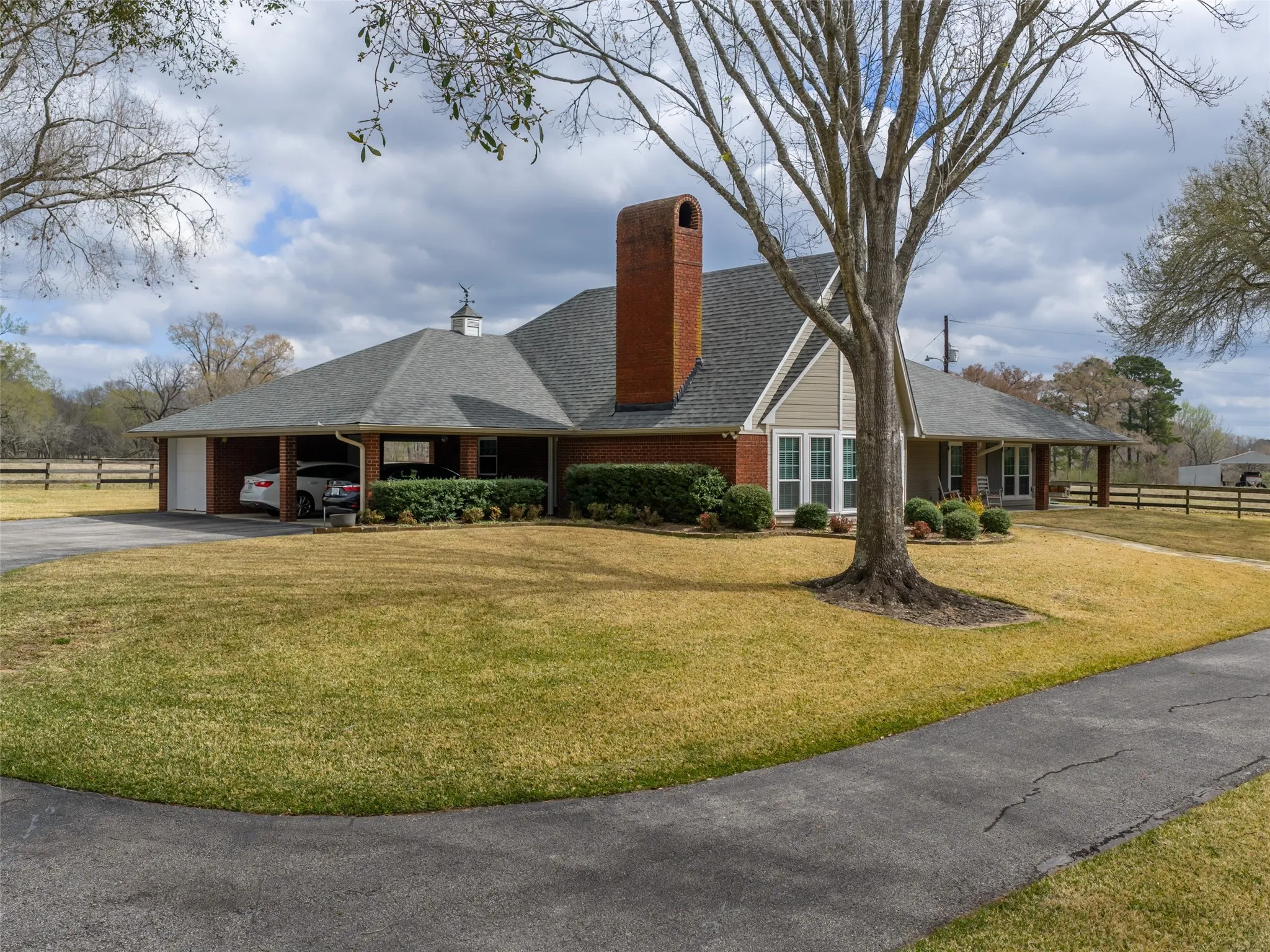 Brick exterior with a prominent chimney, covered carport, and attached garage