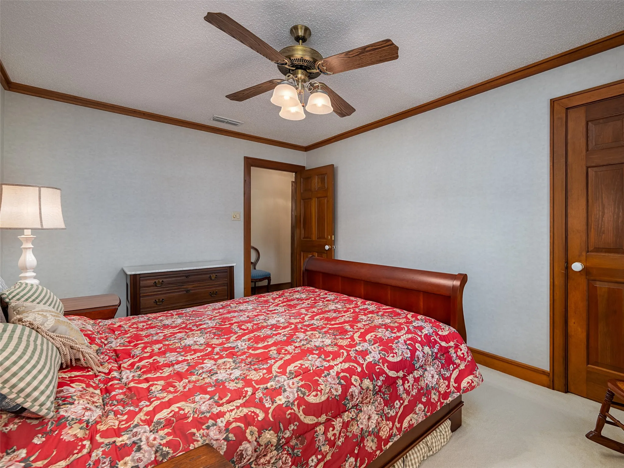 Wood-finish doors and trim, ceiling fan with integrated lighting, textured wall finish, and neutral carpeting