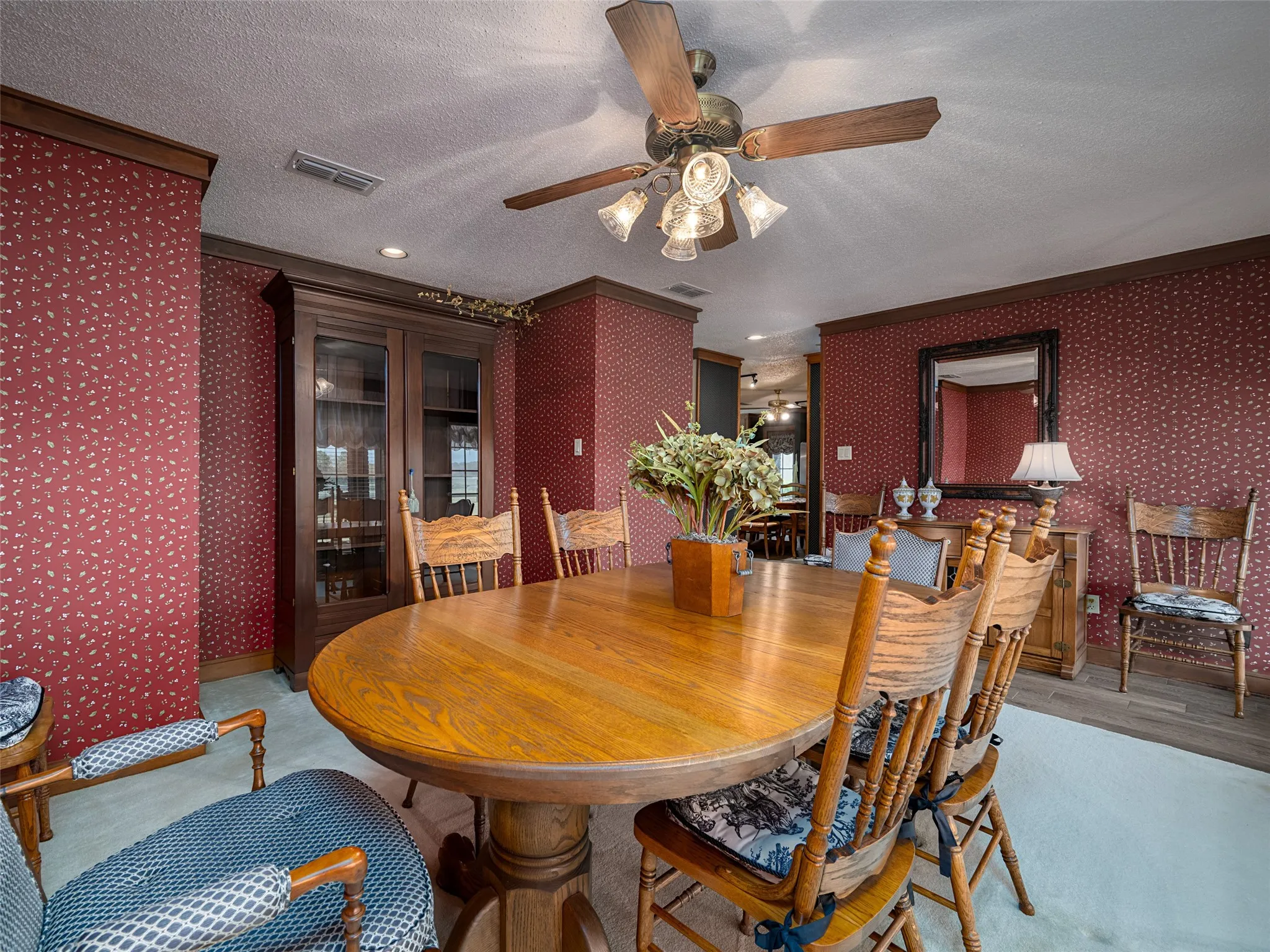 Wood-finish flooring, ceiling fan with light kit, built-in display cabinet, and decorative wall paneling