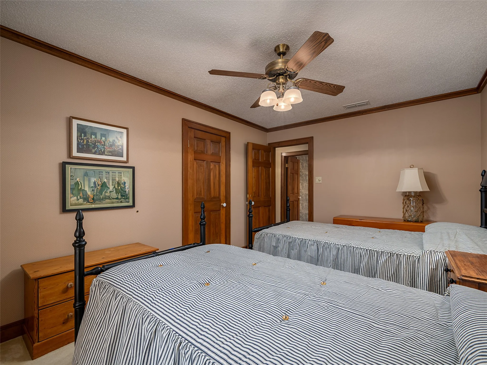 Warm neutral wall color, crown molding, wood-finish doors, and a ceiling fan with integrated lighting